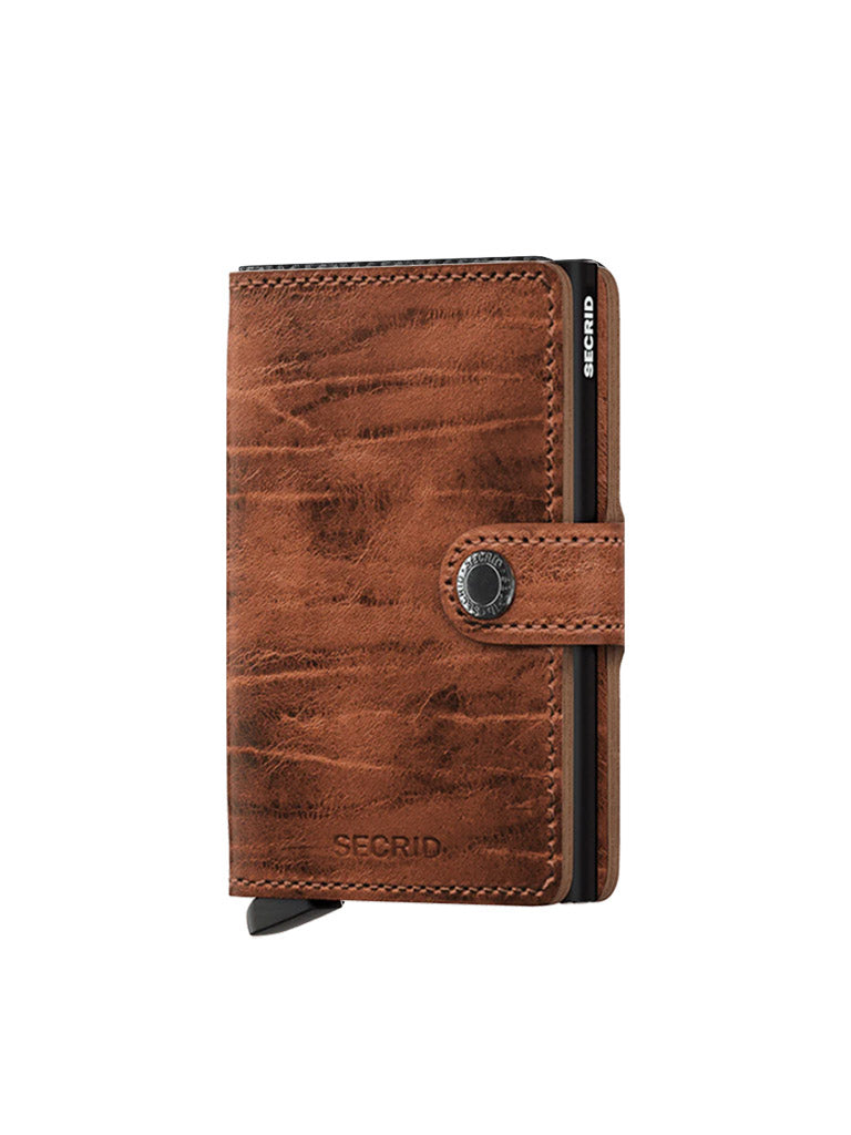 A brown leather Secrid Miniwallet Dutch Martin with a textured finish, button snap closure, and a visible black and silver RFID card holder on the side.
