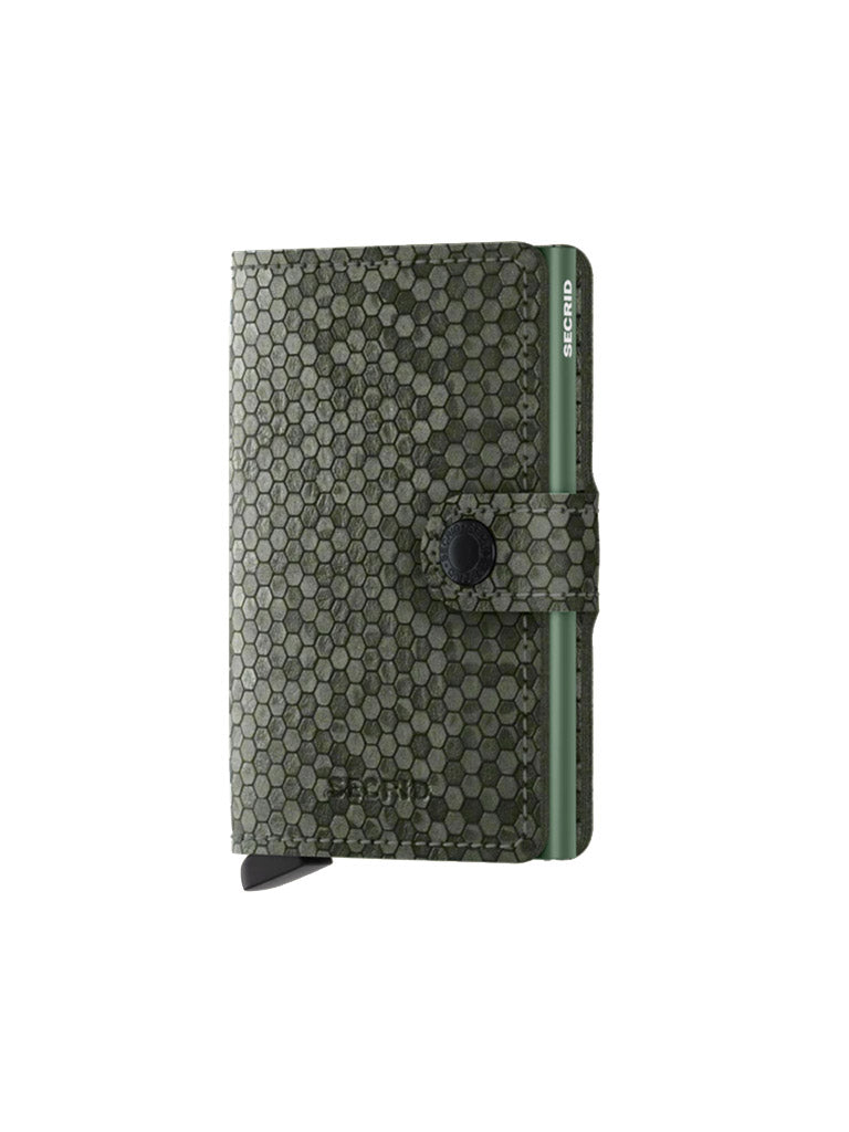The Secrid Miniwallet Hexagon is a compact green leather wallet with a honeycomb pattern, snap-button strap, RFID protection, and side card slider. "Secrid" branding is visible on both the wallet and the card slider.