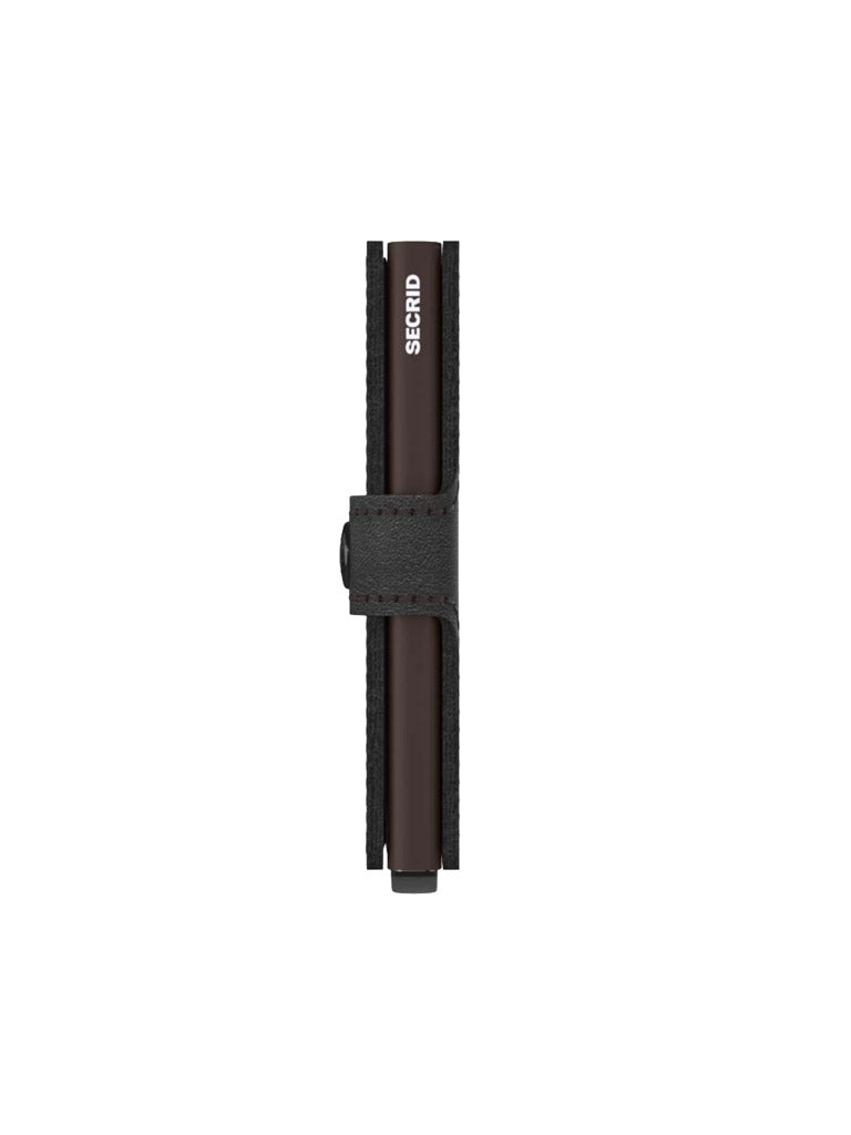A slim, black Secrid Miniwallet Original stands upright, viewed from the side with a textured strap fastened at the center. Made of premium European leather, it features RFID security and “SECRID” branding on the top edge in a minimalist design.