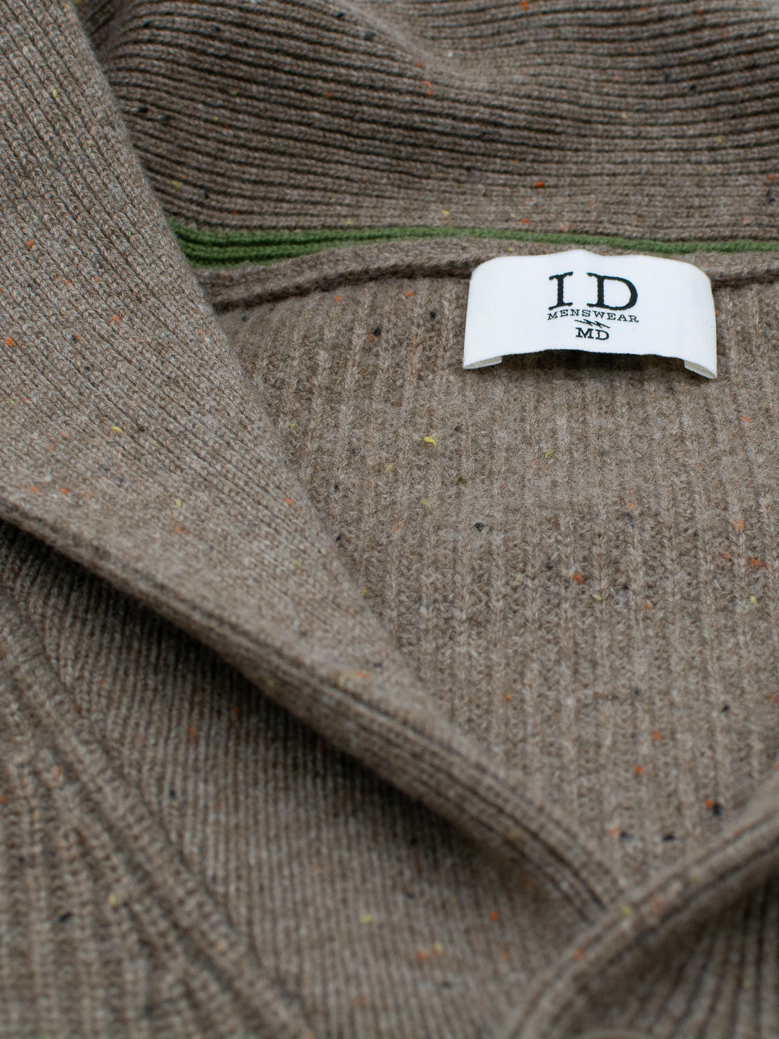 Close-up of the Montreal Merino Wool Cardigan by ID Menswear. The brown ribbed sweater, crafted with speckled yarn, weaves in green and orange threads for an understated charm.