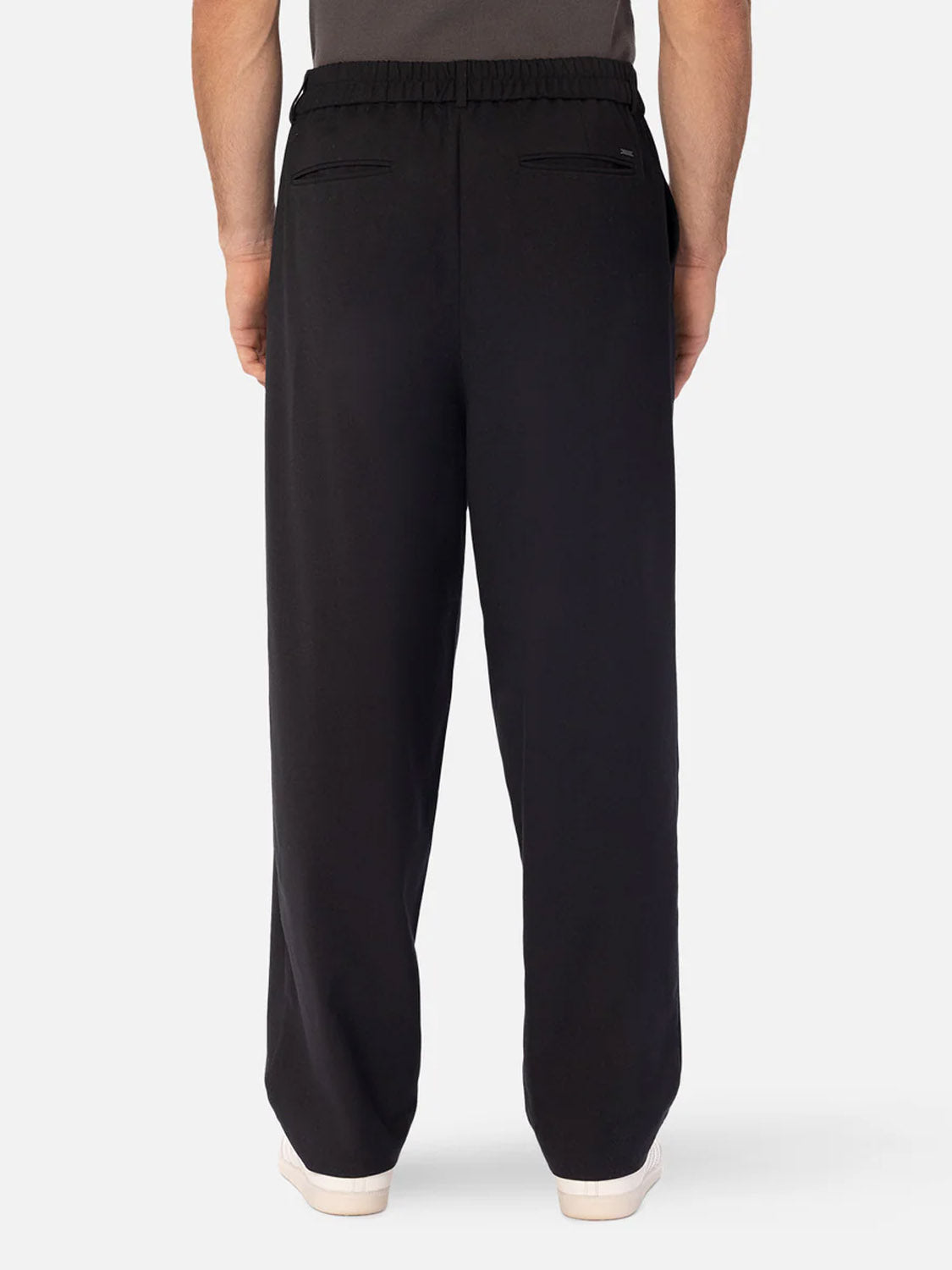 A person is seen from the waist down in Industrie’s The New Milano Pants - Loose Fit, featuring an elastic waistband and welt back pockets. They stand facing away in white shoes against a plain background, showcasing a smart casual style.