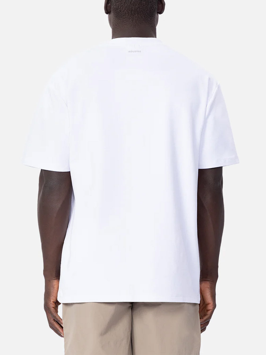 A person is shown from the back against a plain light background, wearing Industrie’s The Newport T-Shirt in plain white with light beige shorts.