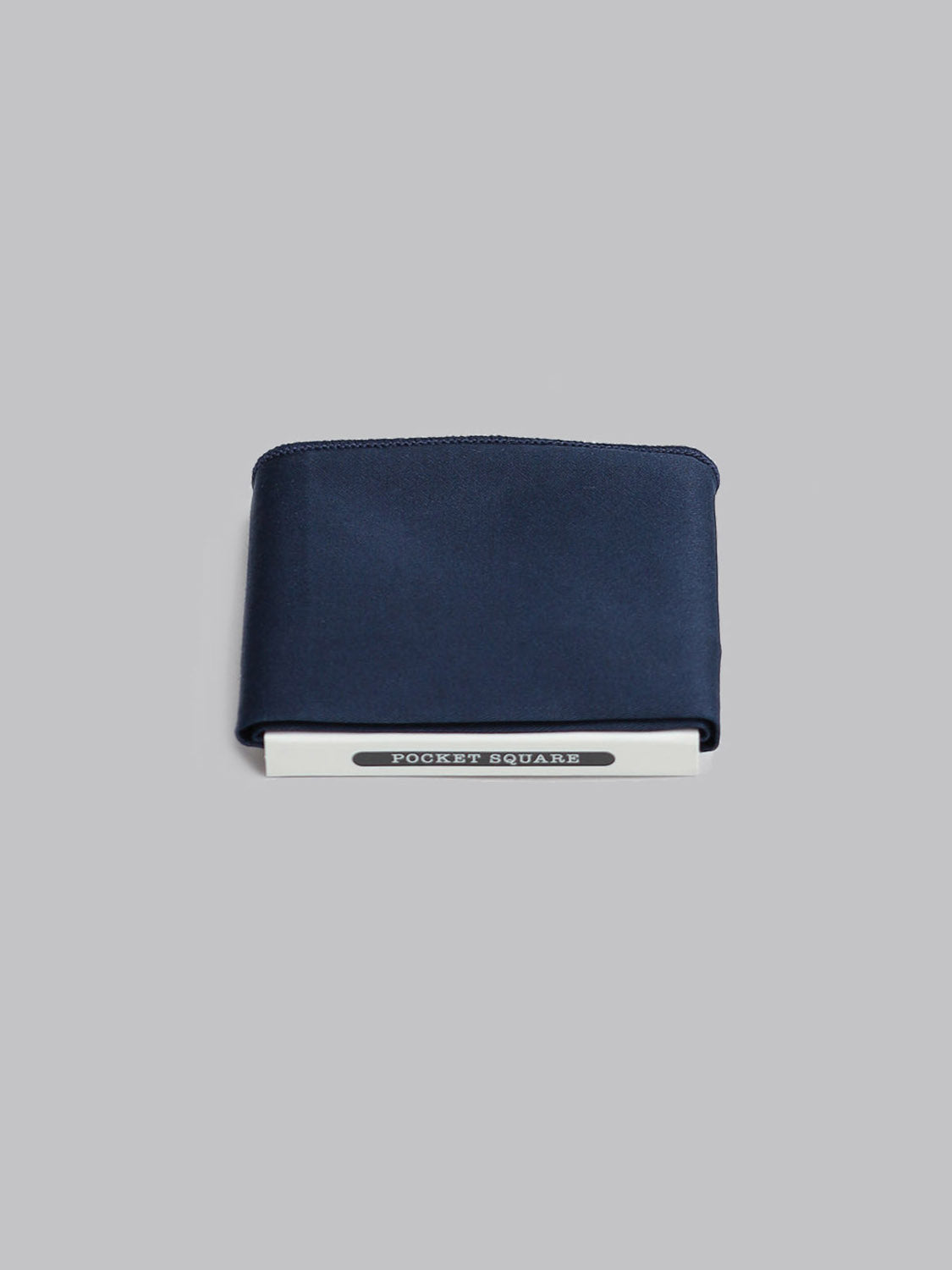 The Night Pocket Square by ID Menswear, handmade in Brooklyn from 100% cotton in navy blue, is neatly folded atop a white POCKET SQUARES box against a plain light gray background.