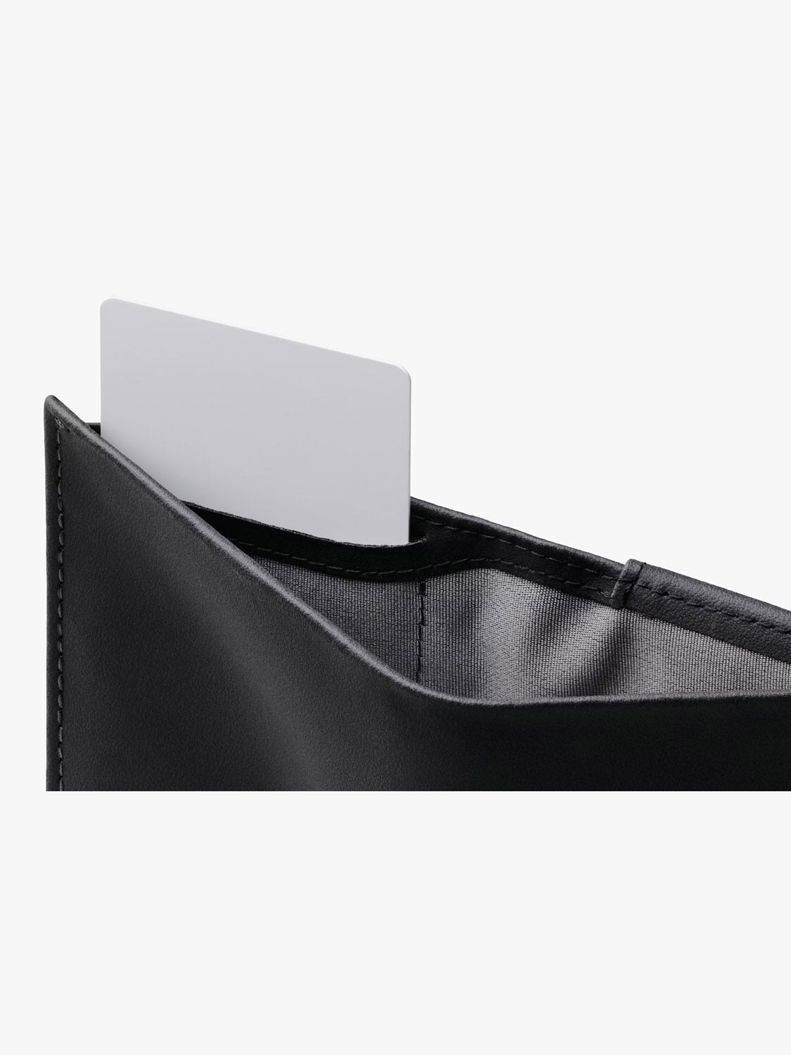 A close-up of a black Bellroy Note Sleeve Innovera™ Edition wallet with RFID protection, showing a plain white card partially visible in one of the slots against a white background.