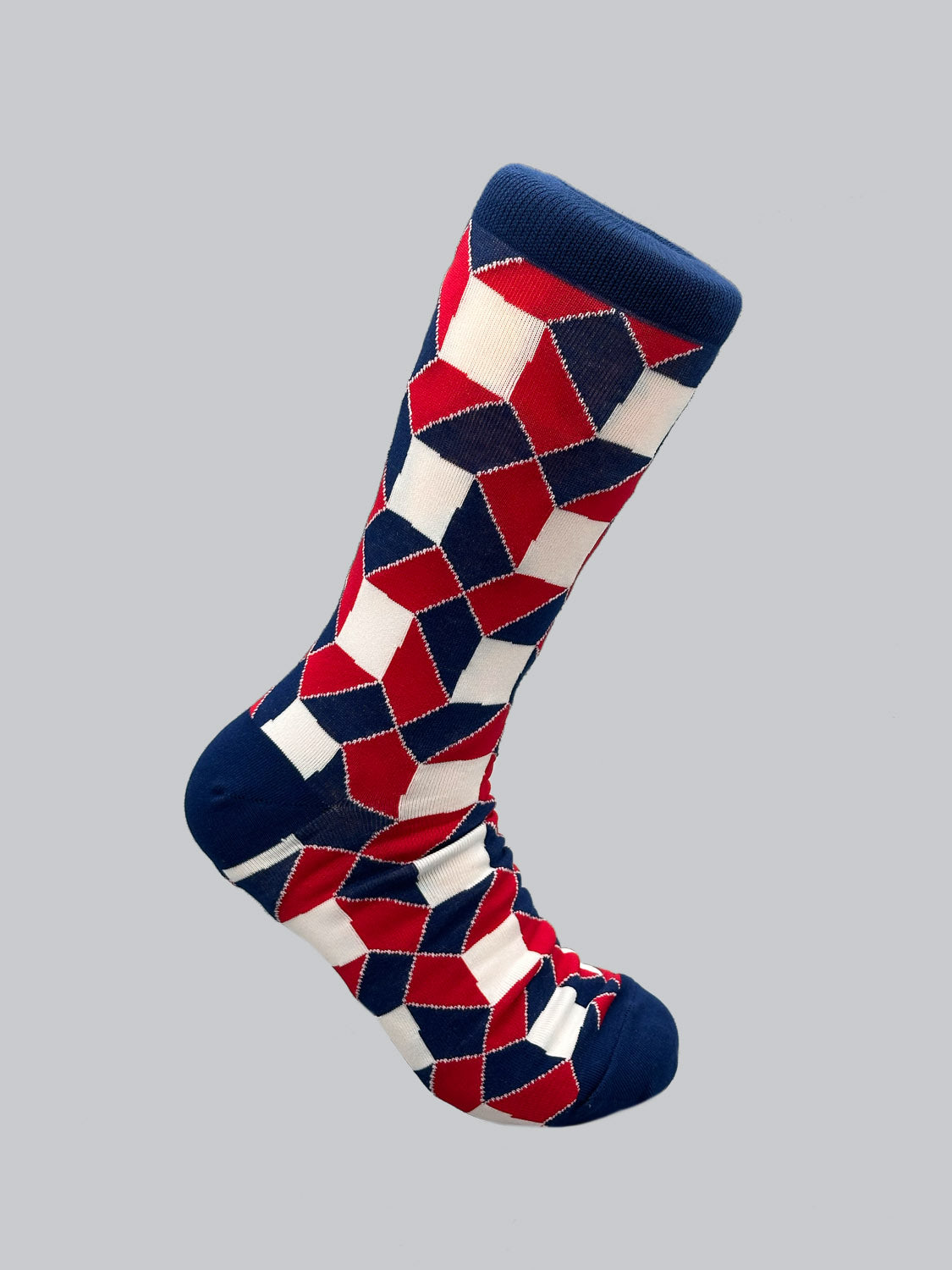 The Octto Graphic Sock by ID Menswear, made from soft combed cotton, flaunts red, white, and blue geometric patterns. Suitable for mens shoe sizes 8-12, it features a solid blue toe, heel, and cuff on a gray background.