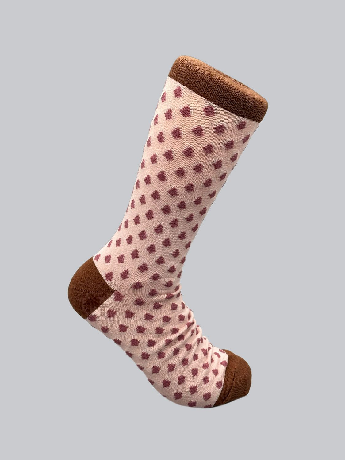 The Ogawara Graphic Sock by ID Menswear is made from premium combed cotton, showcasing maroon squares on a light pink background with brown accents on the toe and cuff. Breathable and stretchy, its displayed against a plain neutral backdrop.