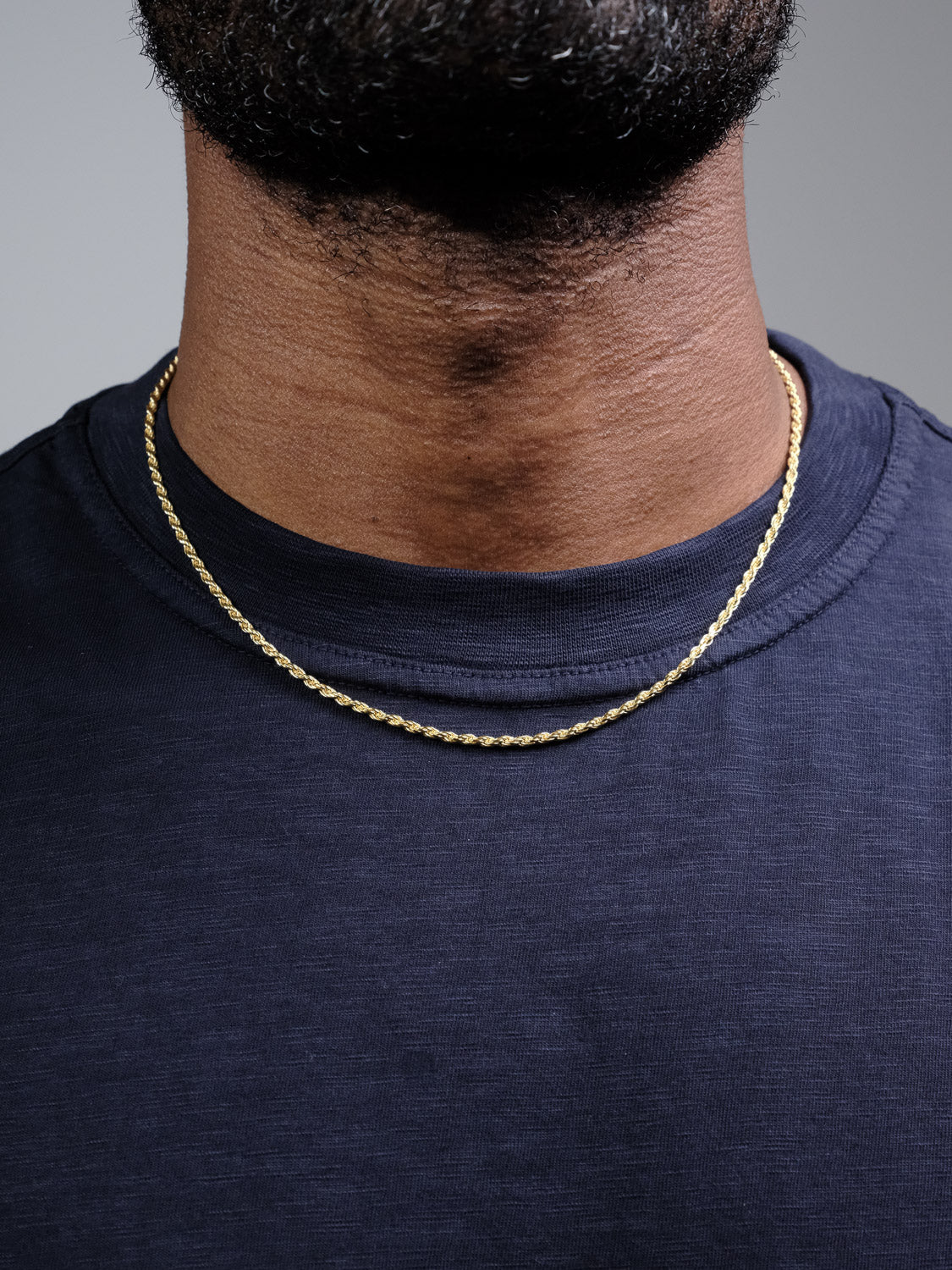 Close-up of a person wearing a dark blue t-shirt and the ID Menswear Orion 50 Rope Chain Necklace, crafted from 4mm Sterling Silver. The image highlights the neck and upper chest. Made in Italy craftsmanship.