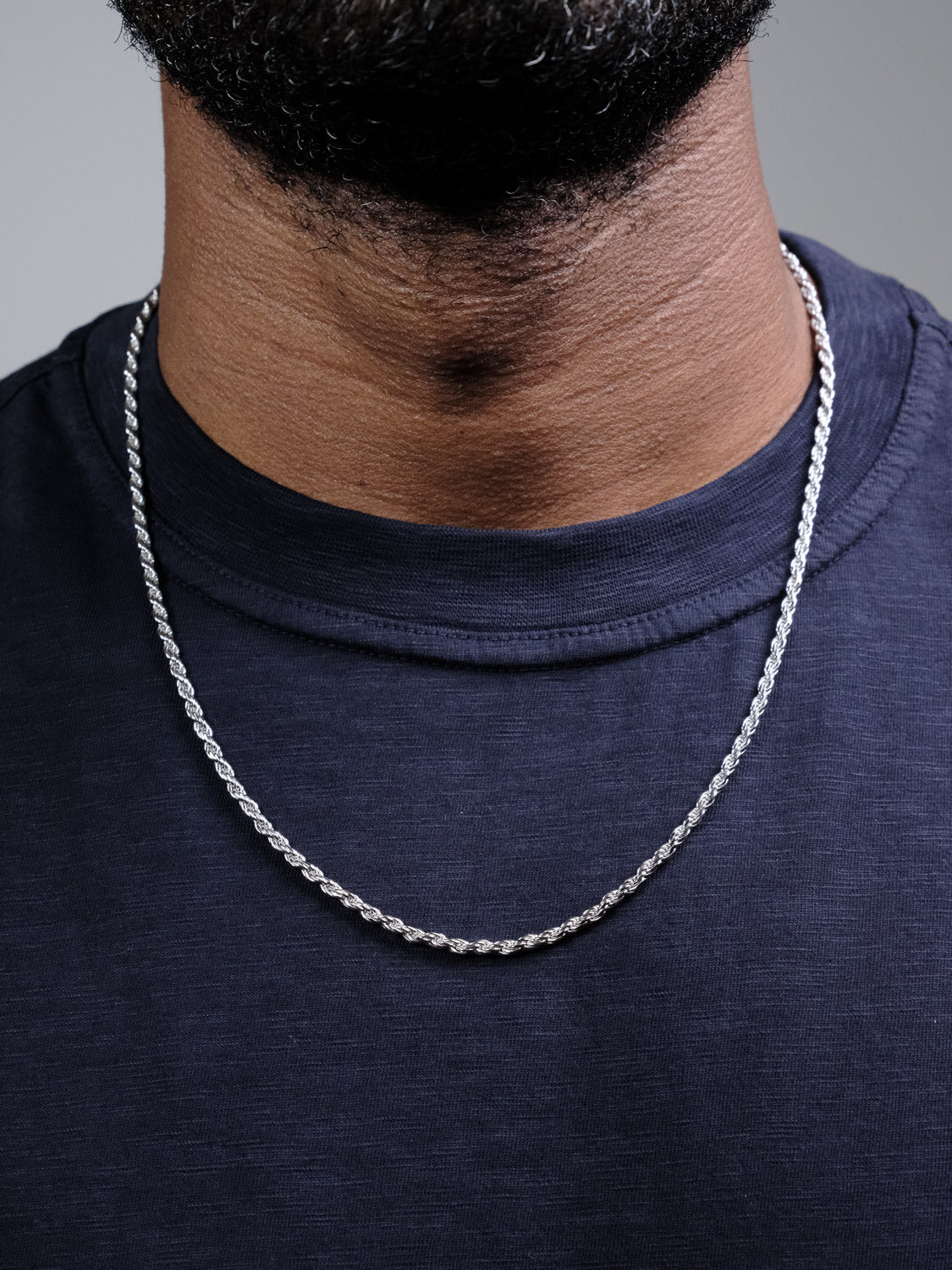 A close-up of a person wearing the Orion 60 Rope Chain Necklace by ID Menswear with a dark navy crew-neck shirt. The image focuses on the neck and upper chest, and the face is not visible.