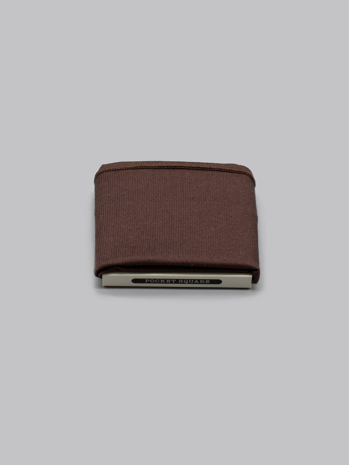 A folded brown Paris Pocket Square by ID Menswear sits on a white holder labeled POCKET SQUARE, set against a plain gray background.