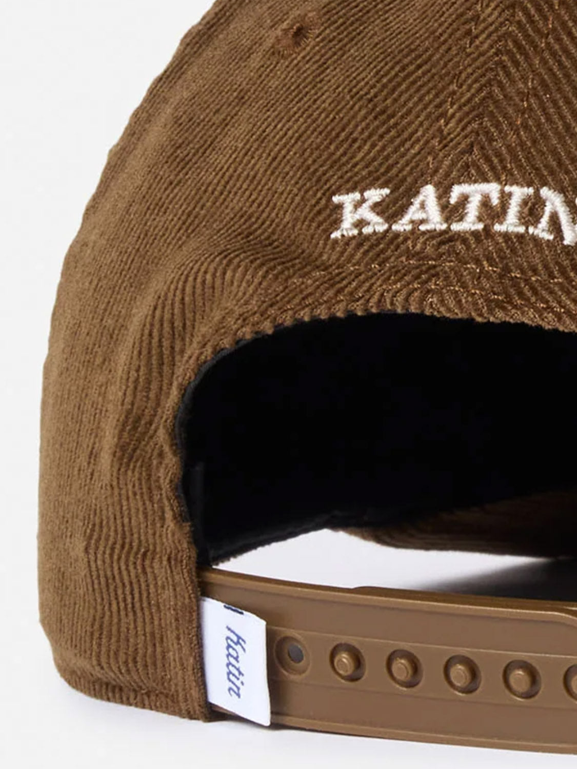 Close-up of the back of the Katin Peaks Hat, a brown cotton corduroy 5-panel cap featuring white embroidered "KATIN" text, a white tag with blue "katin" script, and a classic snapback closure.