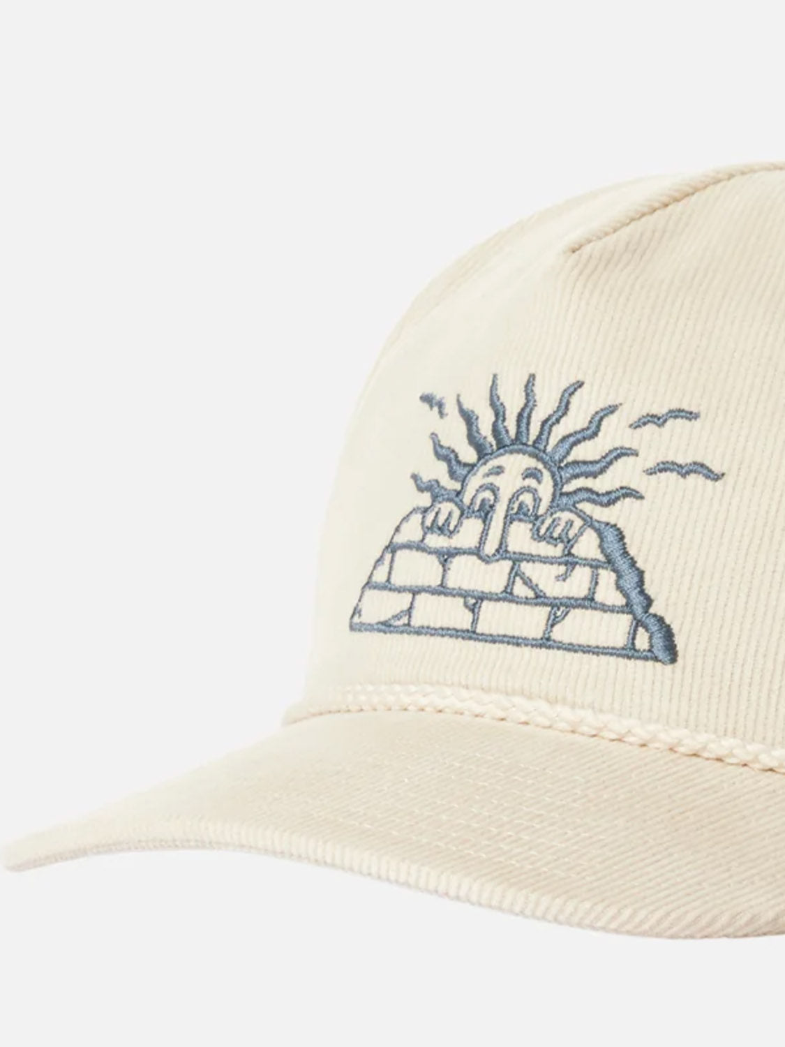 The Katin Peaks Hat is a beige cotton corduroy 5-panel cap with an embroidered sun face over a brick wall, shown on a plain white background.