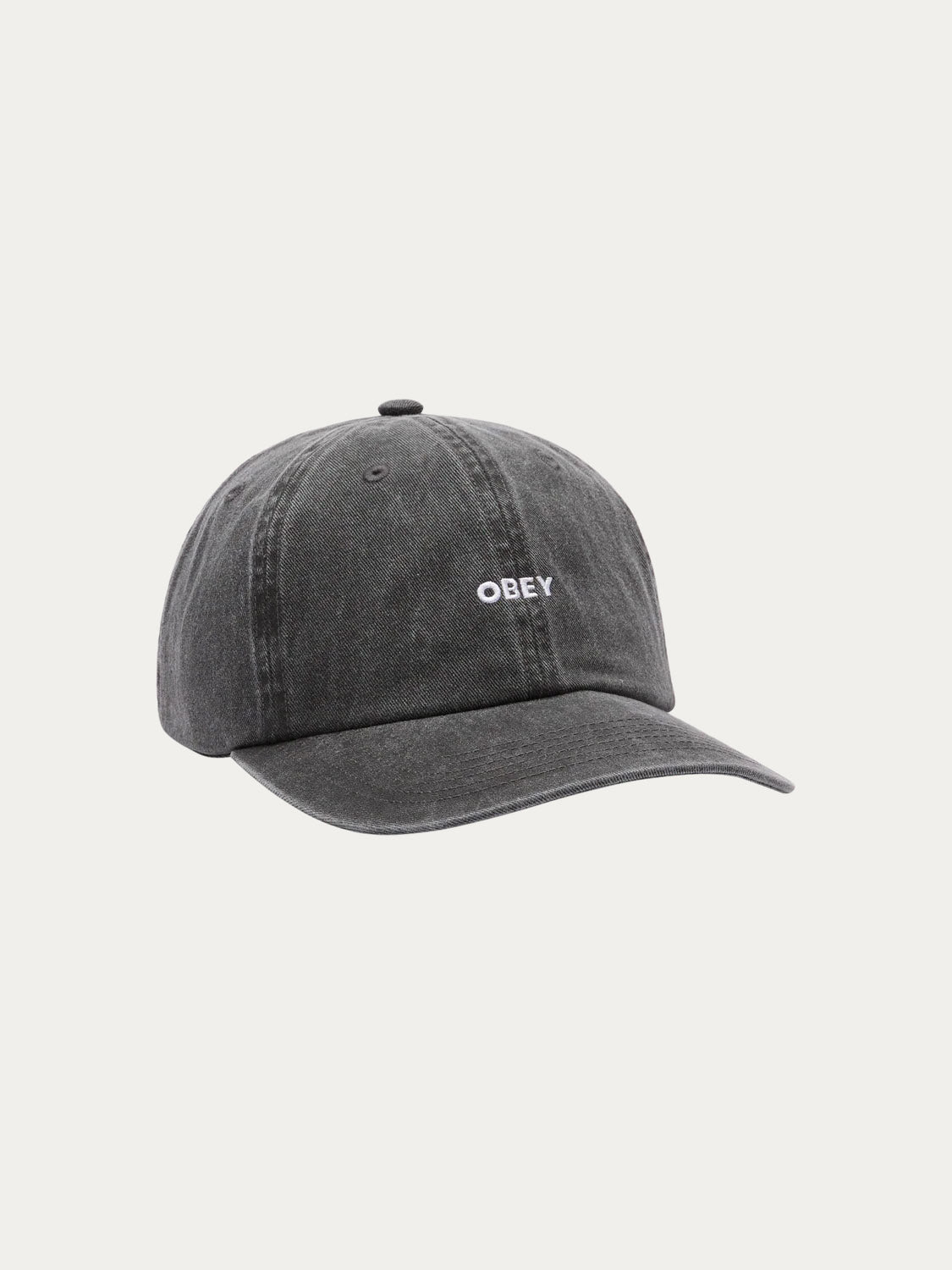 The Obey Pigment Bold 6 Panel Strapback is a black, slightly faded 100% cotton baseball cap with a small white embroidered Obey logo on the front. This strapback hat has a curved brim and is shown on a plain white background.