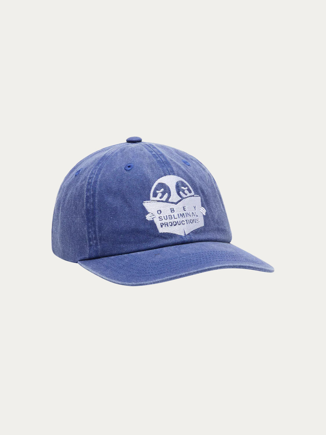 The Obey Pigment Productions SNPB is a blue baseball cap with white OBEY art embroidery and "OBEY SUBLIMINAL PRODUCTIONS" text on the front, featuring a precurved brim and shown on a plain white background.