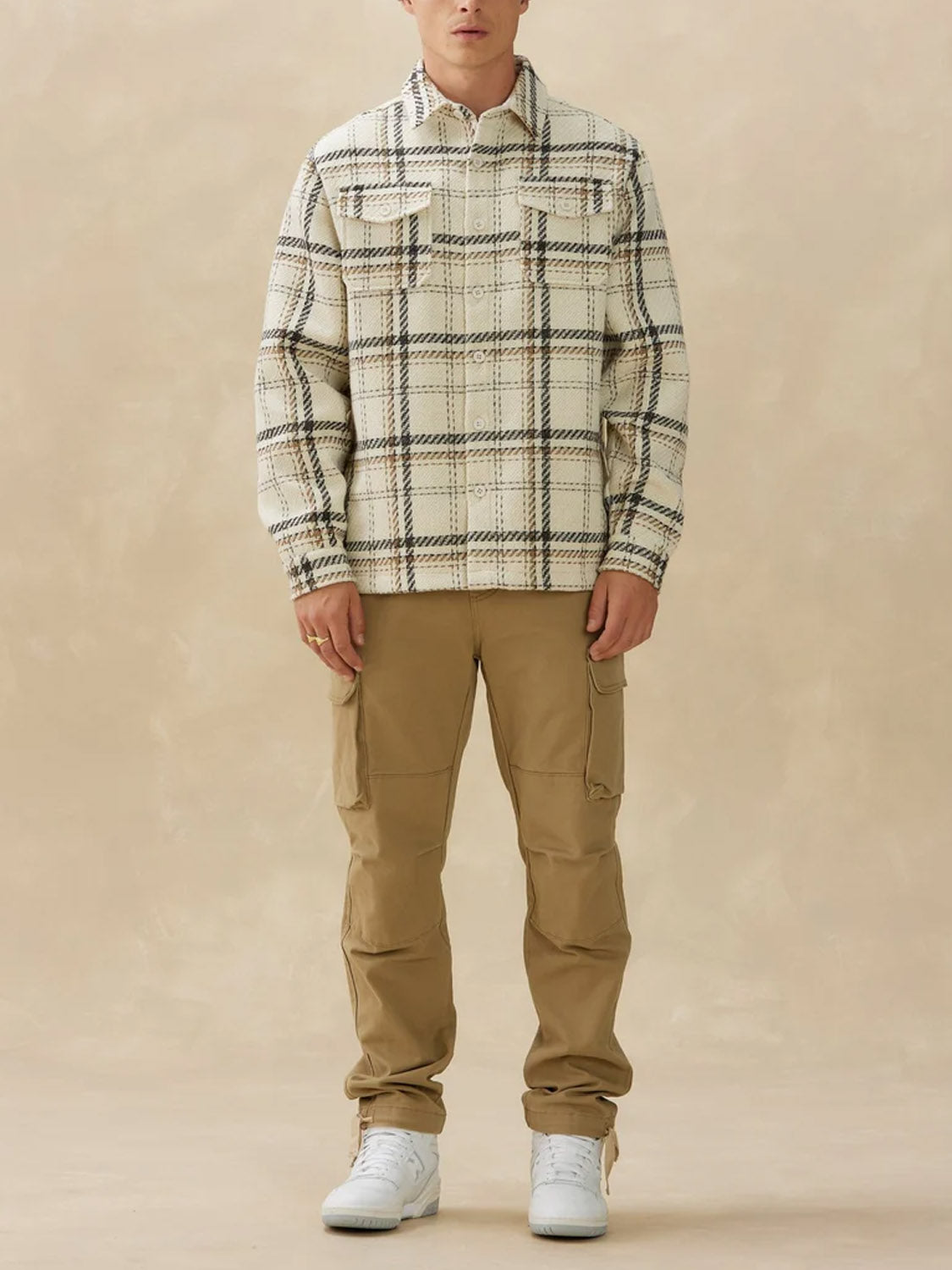 A person wearing a Kuwalla Heavyweight Plaid Shirt in beige, khaki cargo pants, white high-top sneakers against a plain beige background.