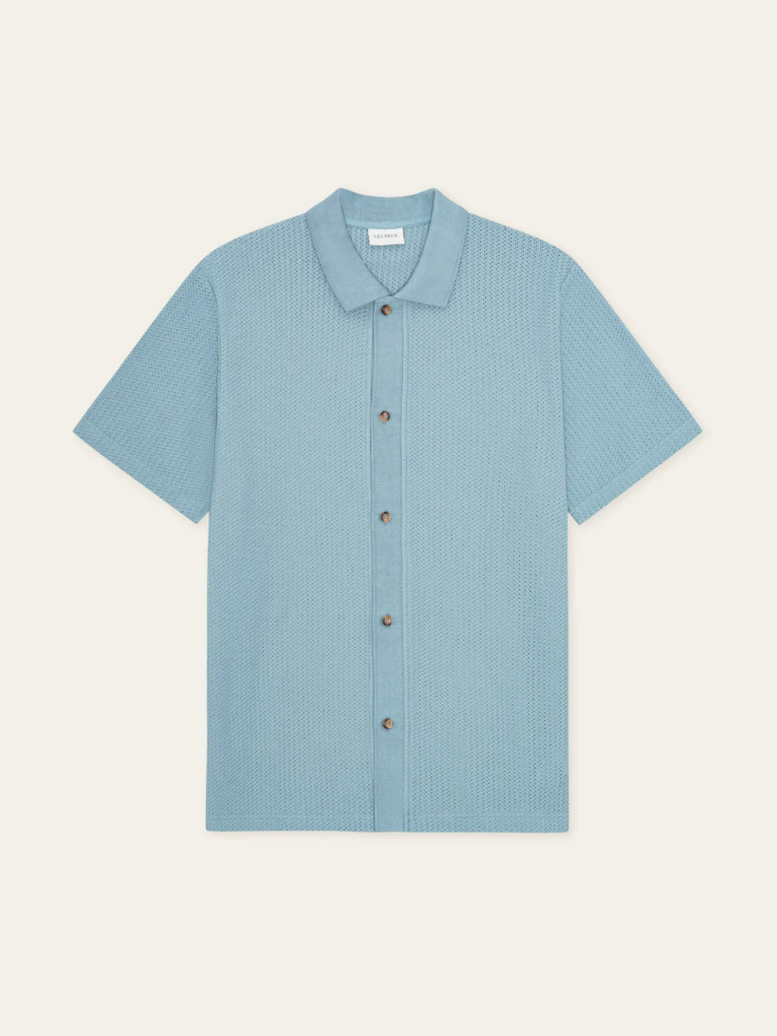 The Les Deux Pointelle SS Shirt, a light blue organic cotton camp collar shirt with a textured pattern and short sleeves, is laid flat on a plain off-white background.