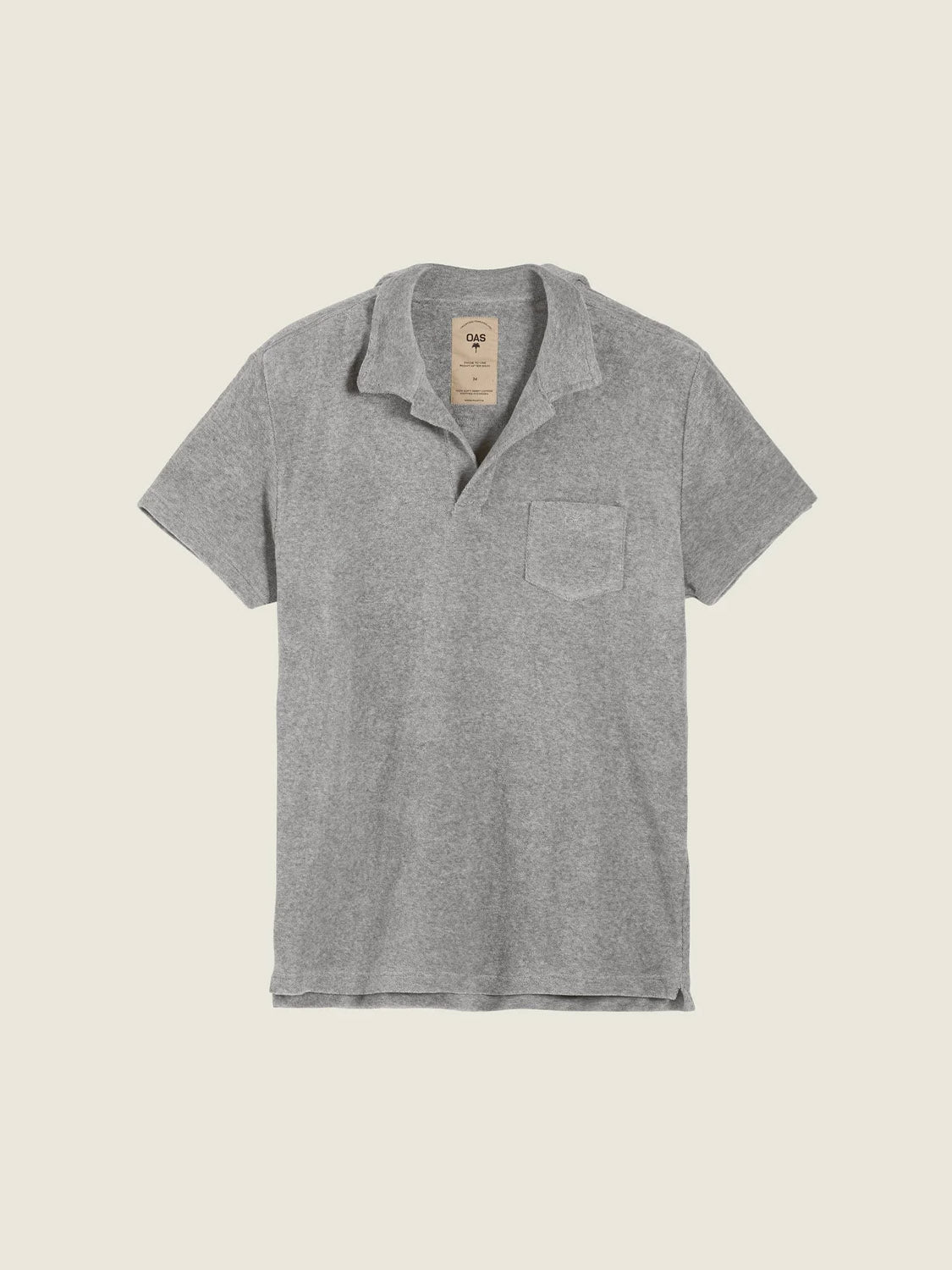 The OAS Polo Terry Shirt in heather gray features breathable cotton terrycloth, short sleeves, a chest pocket, relaxed collar, and a beige neck tag with text. It is shown laid flat on a light background.