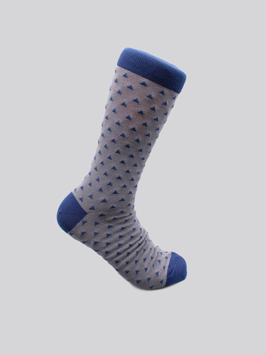 The Polygon Graphic Sock by ID Menswear features a gray base with small blue triangles, solid blue cuffs, toe, and heel. Made from premium combed cotton for mens shoe size 8-12, it’s shown on a plain light gray background.