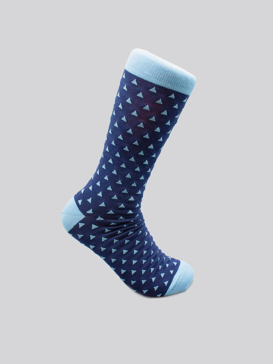 The Polygon Graphic Sock by ID Menswear in navy blue with light blue toe, heel, and cuff features small triangles. Made from premium combed cotton, it fits mens shoe sizes 8-12. Shown on a light grey background.