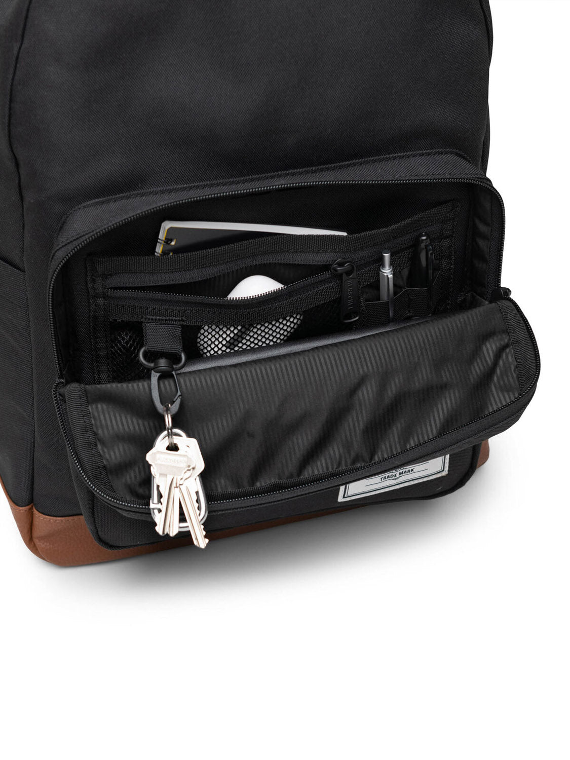 A close-up of an open Herschel Pop Quiz Backpack shows organized items—keys on a key clip, pens, and a notebook—neatly arranged atop the brown base of this recycled backpack made with durable EcoSystem fabric.