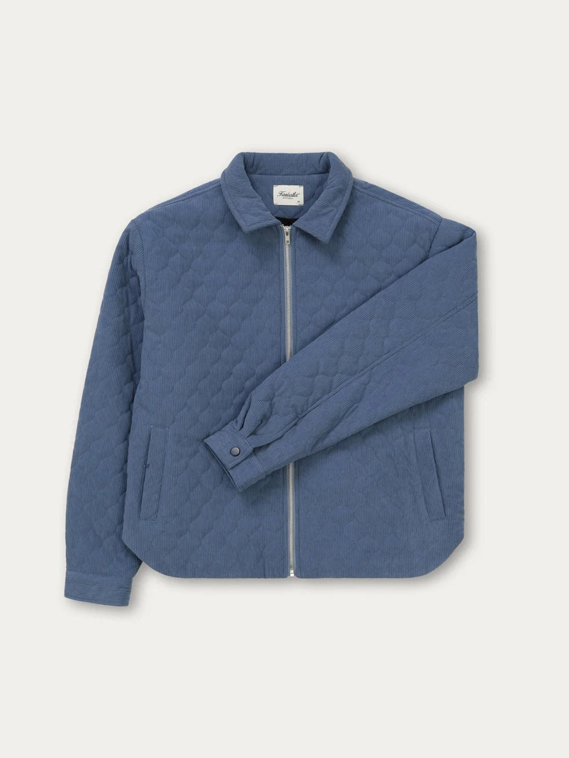 The Kuwalla Quilted Corduroy Shacket in blue features a quilted design, front zipper closure, collar, long sleeves, and two side pockets. It is shown laid flat on a white background.