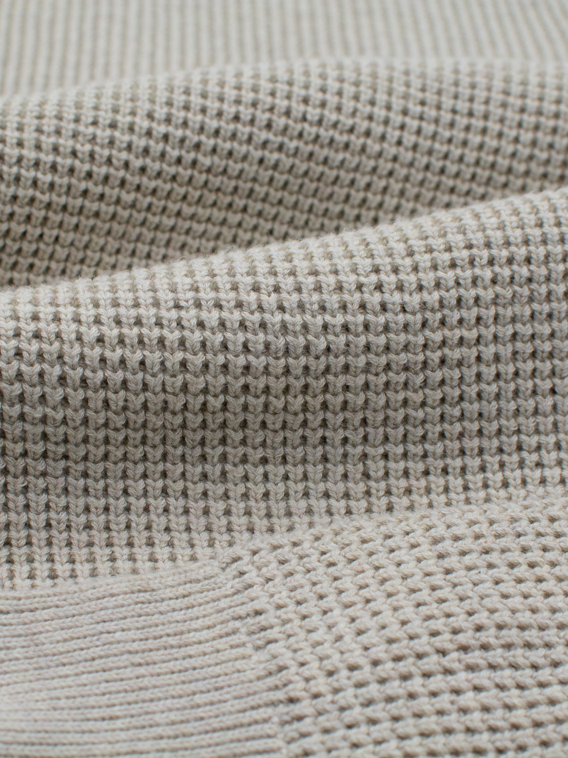 Close-up of ID Menswears Ragnar Waffle Knit Sweater in light beige, showcasing its 100% cotton fabric with a textured waffle-knit pattern. The image highlights the soft ridges and folds, emphasizing craftsmanship, comfort, and quality.