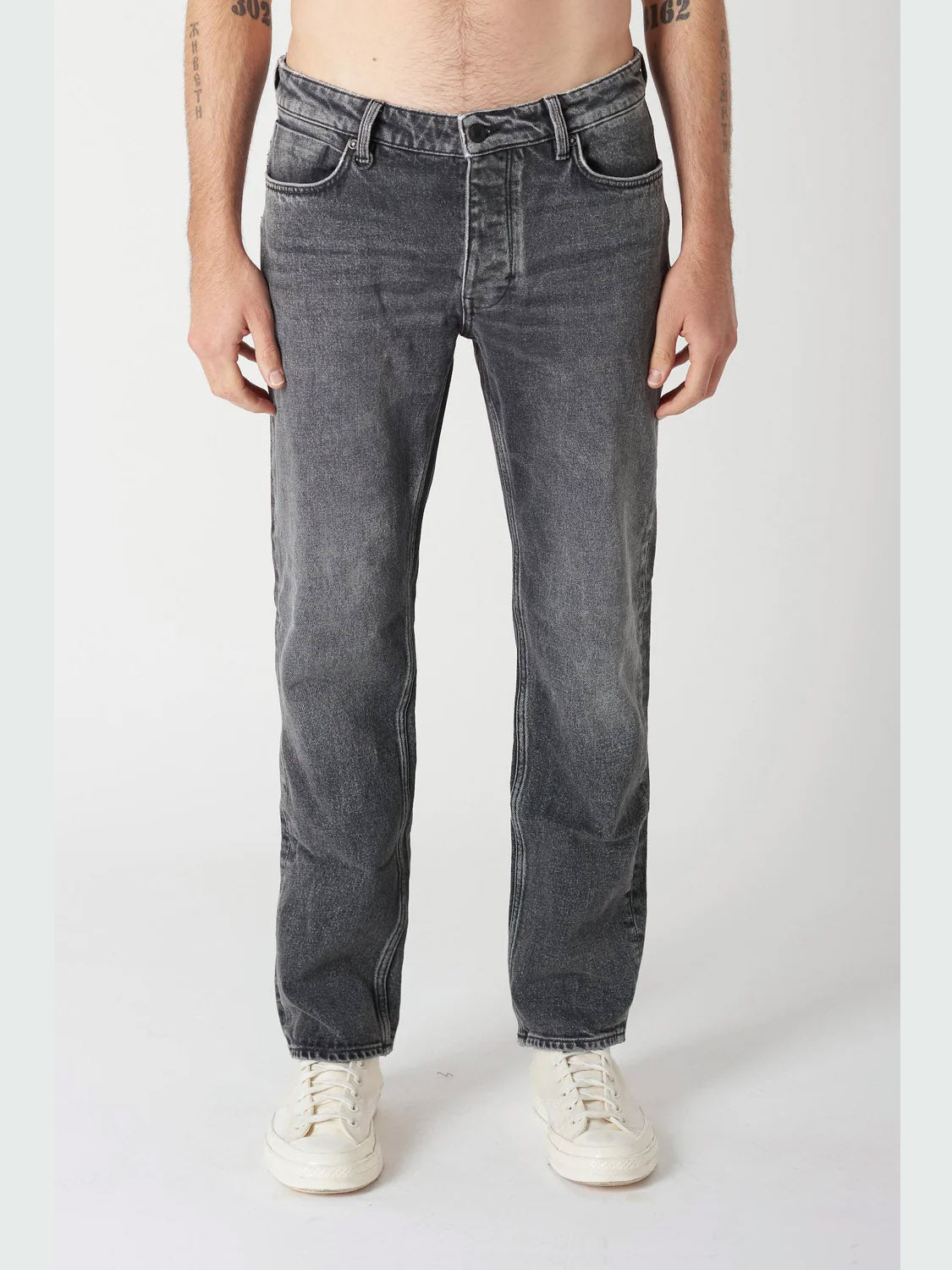 A person in Neuw Ray Straight Dead Moon jeans and white sneakers stands against a plain white background; their upper body is partially out of frame.