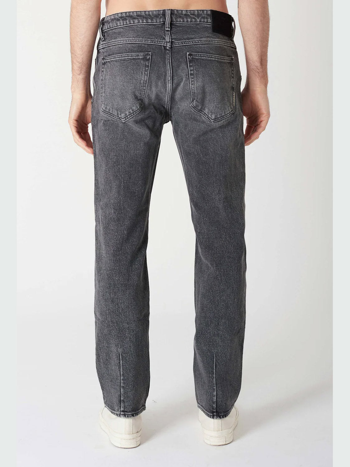 A person is shown from the back, standing against a plain white background, wearing Neuw Ray Straight Dead Moon jeans and white sneakers.