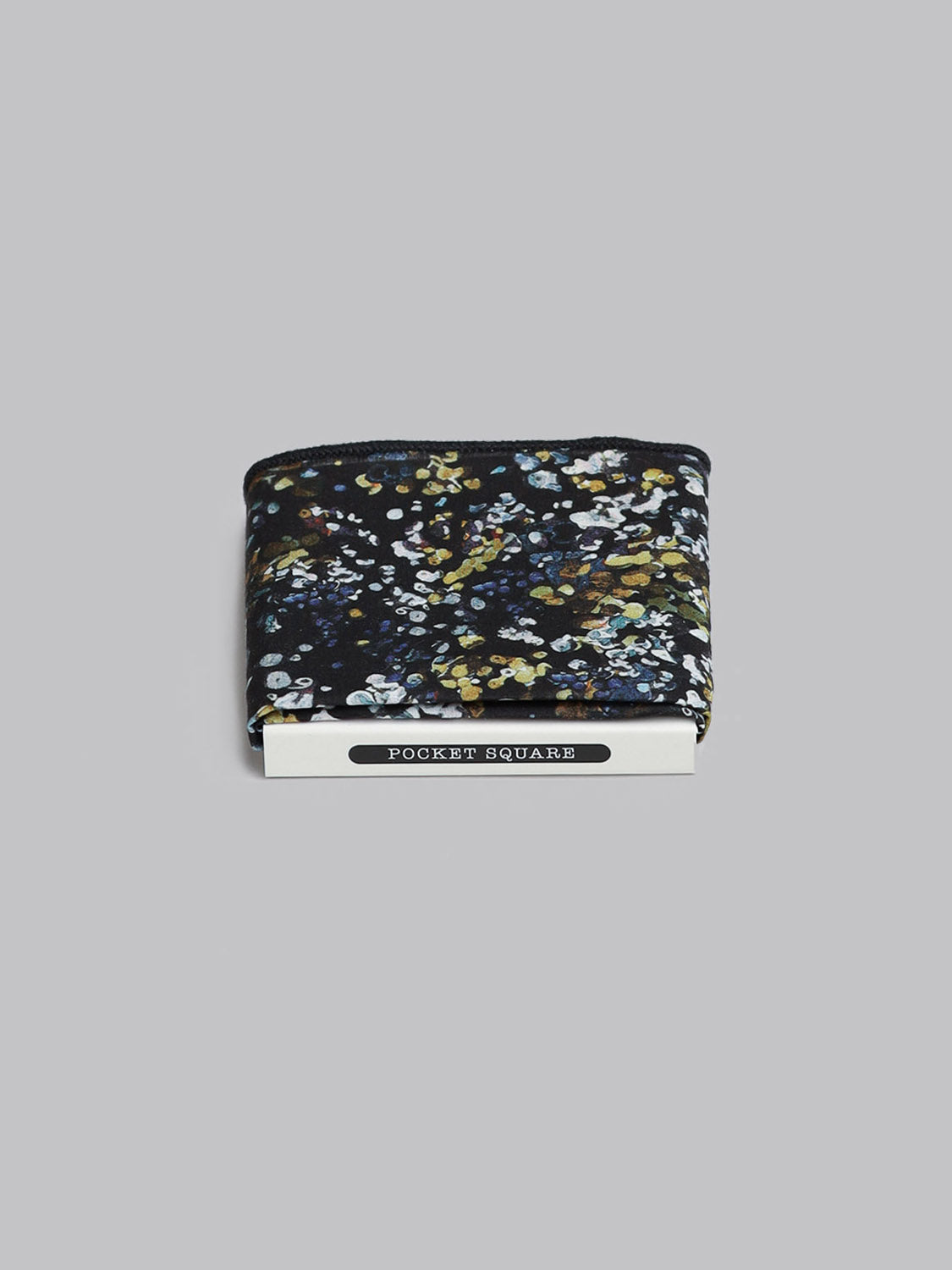 The Liberty™ Reflection Pocket Square by ID Menswear—a handmade Tana Lawn cotton accessory with yellow, white, and blue floral patterns—lies folded against a plain light gray background.