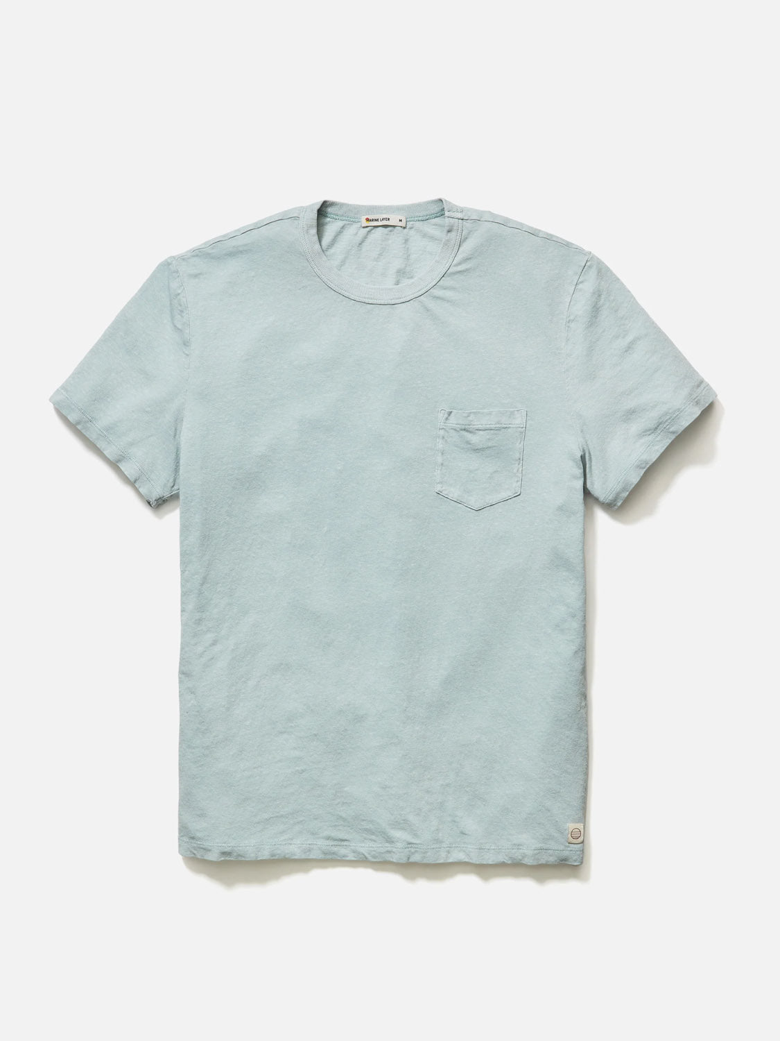 The Marine Layer Relaxed Hemp Cotton Tee in light blue lies flat on a white background, crafted from comfortable cotton, featuring a round neckline and chest pocket.