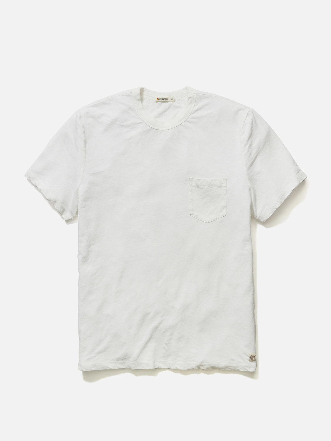 The Marine Layer Relaxed Hemp Cotton Tee by Marine Layer is a white T-shirt with a crew neck and left-side chest pocket. Made from comfortable cotton, it features a slightly textured look.