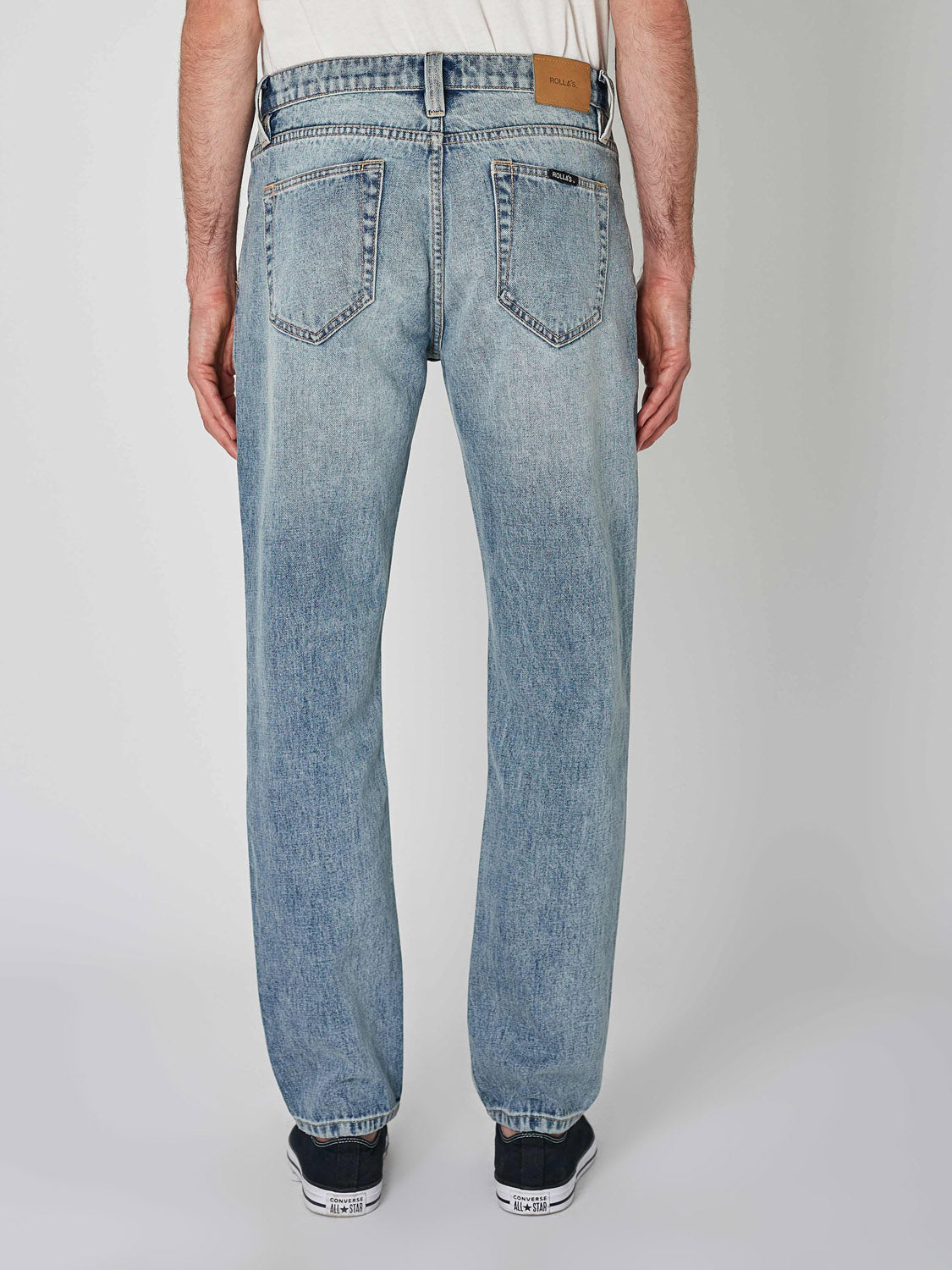 A person wearing Rollas Relaxo Hemp Bleach Vintage Denim jeans and black sneakers is shown from the back against a plain light background. The jeans feature two back pockets and a brown leather patch on the waistband.