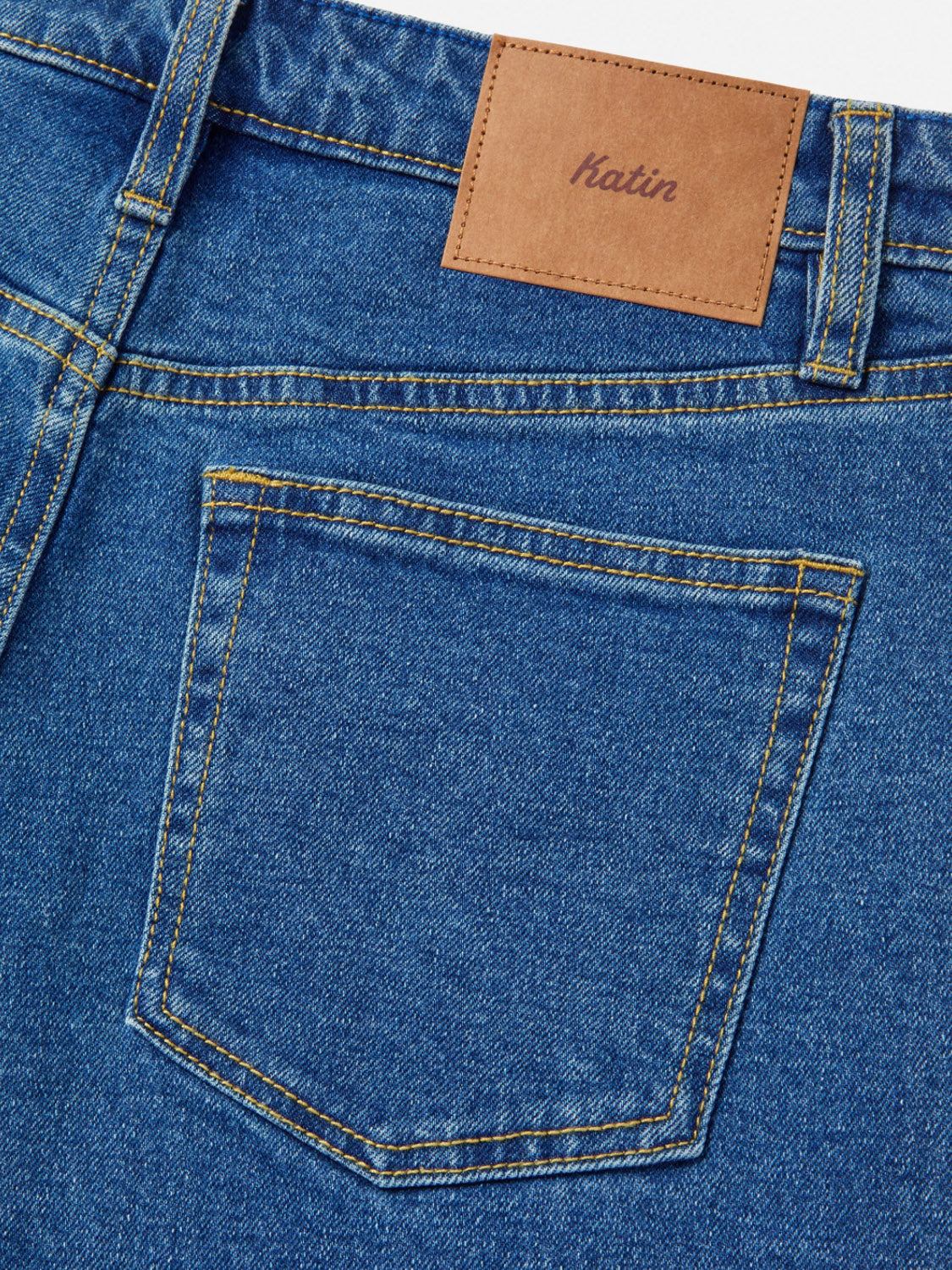 Close-up of the back pocket and waistband on Katin Ren 57 Classic Straight Pants, with yellow stitching, 5-pocket styling, and a brown leather Katin patch above the pocket.
