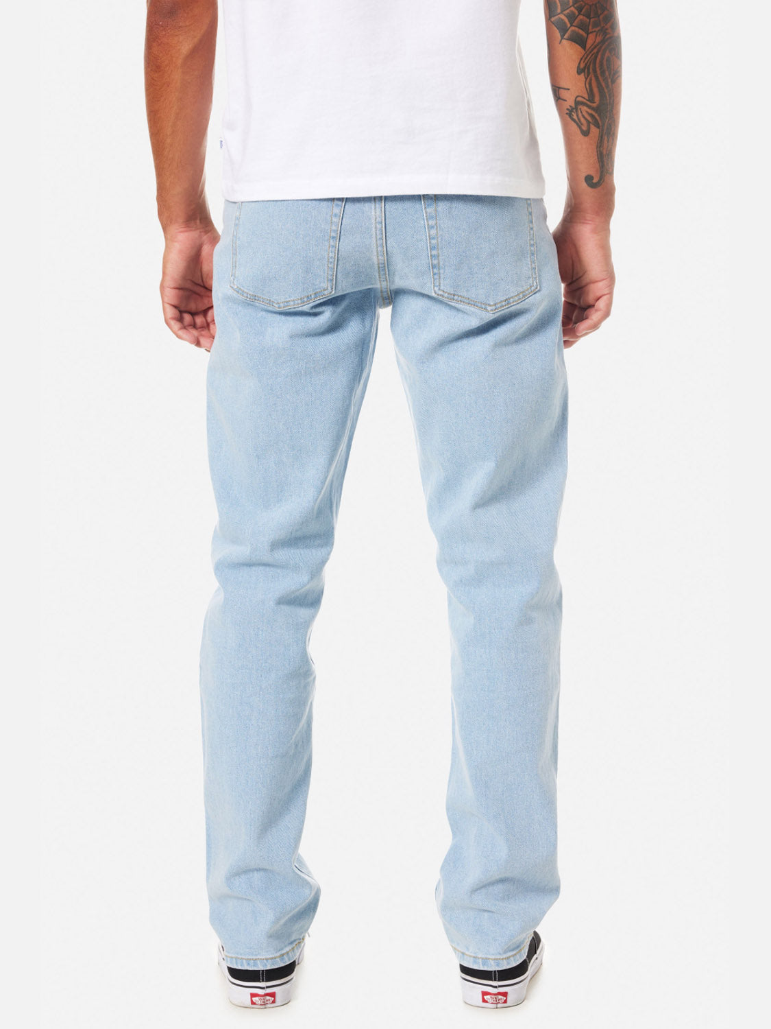 A man is shown from the back wearing Katin's Ren 57 Classic Straight Pants, a white T-shirt, and black-and-white sneakers. He has a tattoo on his left arm, hands by his sides, against a plain white background.