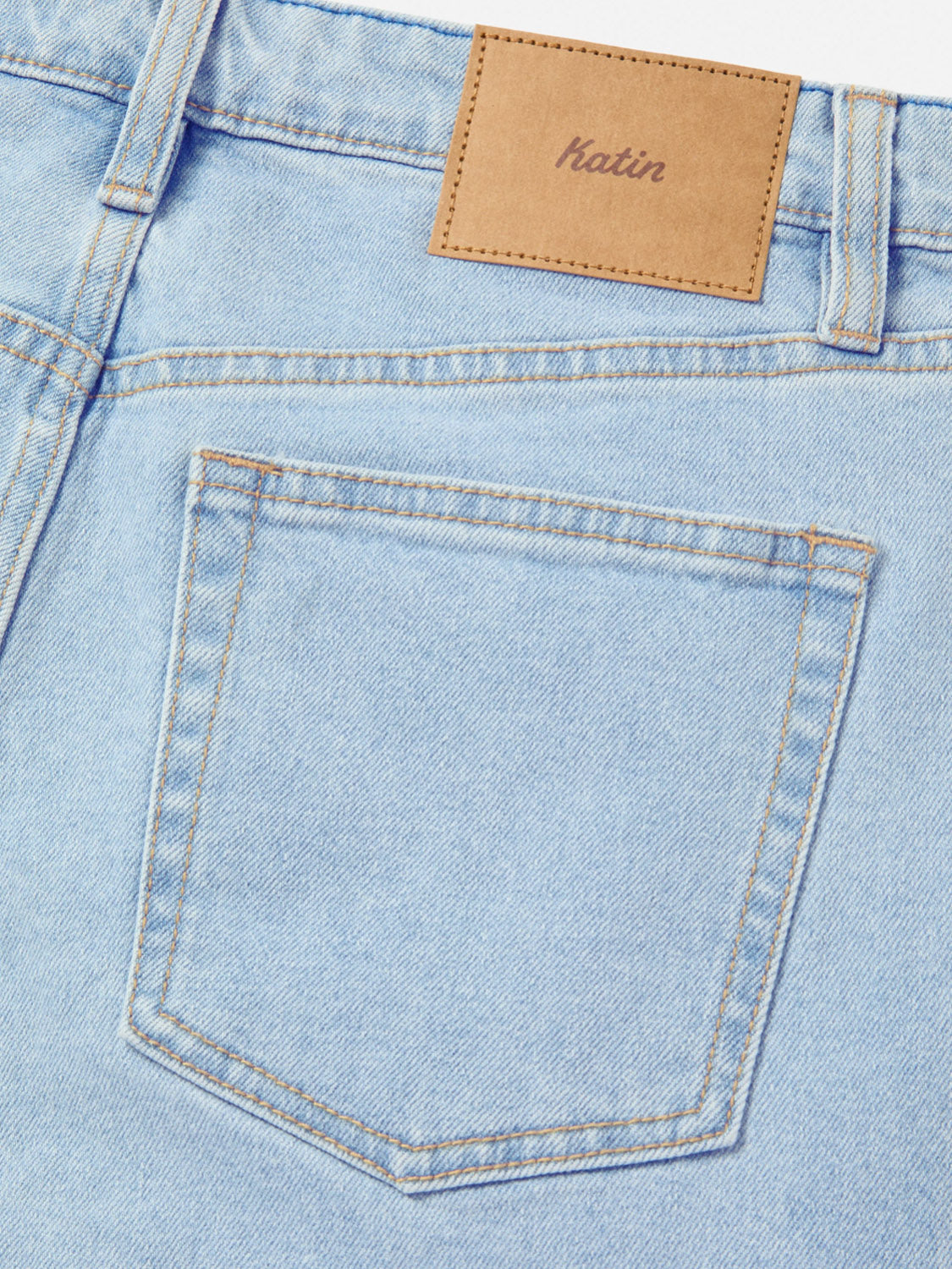 Close-up of the back pocket on Katin Ren 57 Classic Straight Pants in light blue denim, showing 5-pocket styling, tan stitching, and a brown leather patch above the pocket embossed with "Katin.