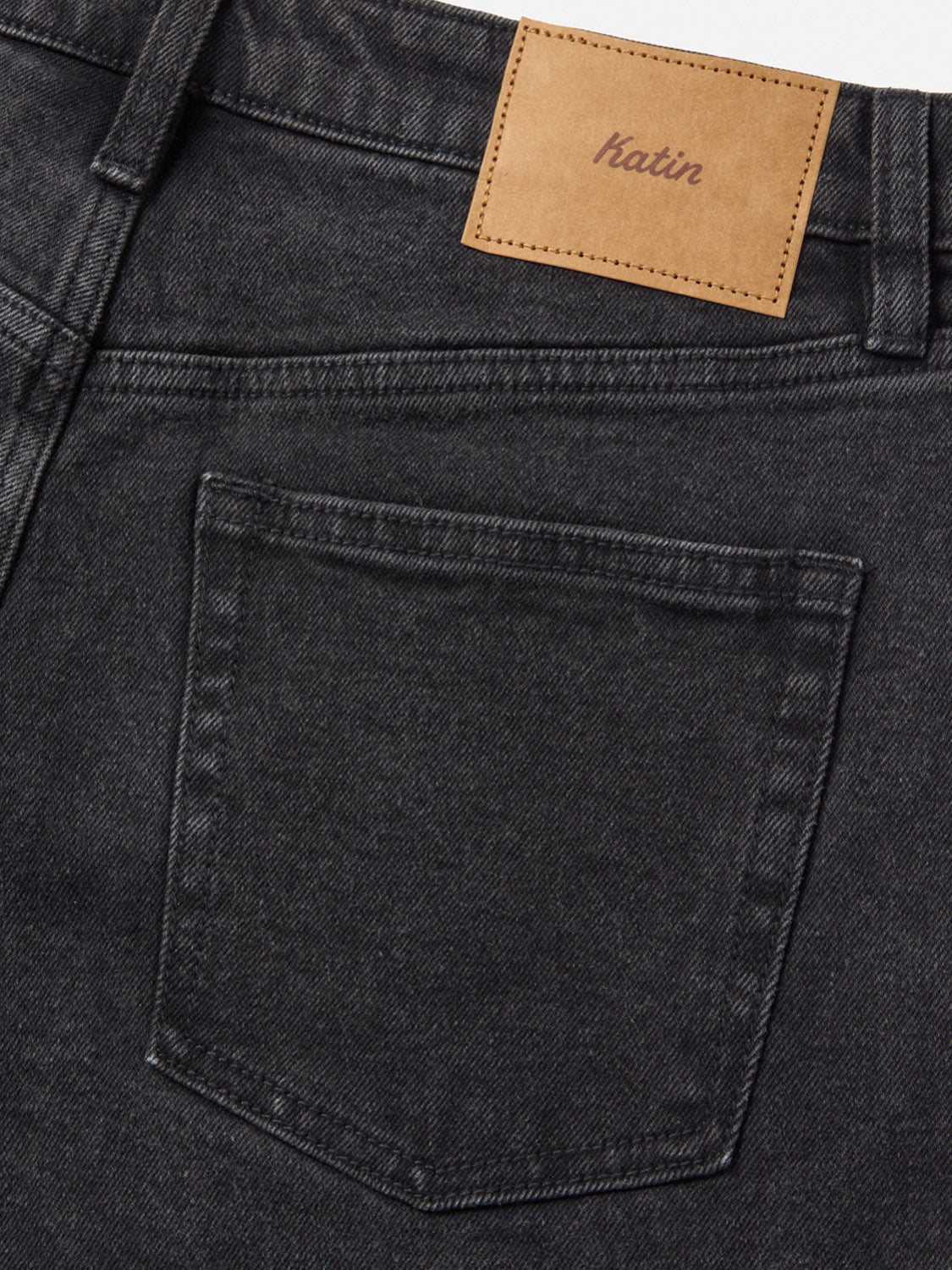 Close-up of the back of Katin Ren 57 Classic Straight Pants in black denim, featuring classic 5-pocket styling, a single back pocket, and a tan leather Katin patch stitched above the waistband.