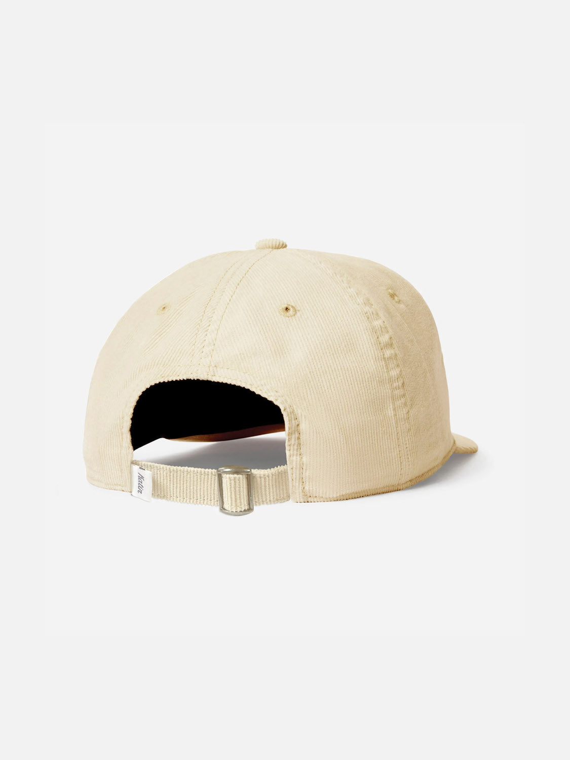 The beige corduroy Katin Retreat Hat baseball cap is shown from the back, highlighting its adjustable strap with a metal buckle and a small fabric tag on the left side—a timeless Katin headwear piece.