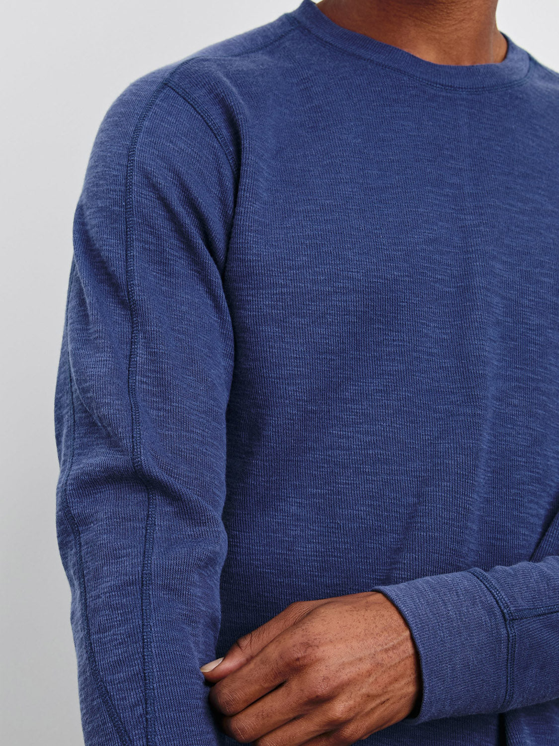 A person stands against a plain background, right arm crossed over to hold their left elbow, wearing a Rails Rheese Long Sleeve Thermal by Rails. The close-up highlights its elegant crewneck thermal design and subtle French rib details, without showing the persons head.