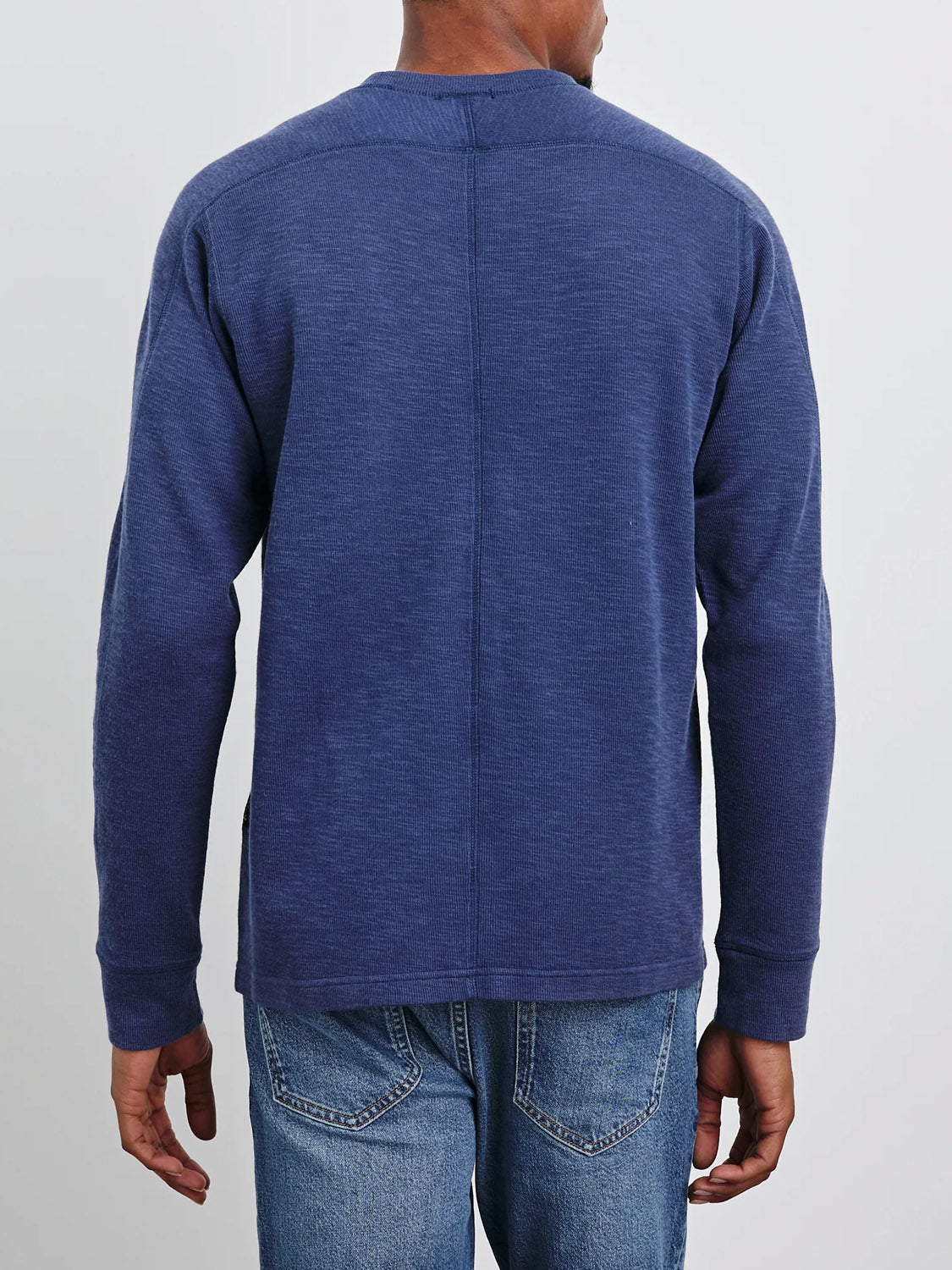 A person is seen from the back wearing Rails Rheese Long Sleeve Thermal in dark blue paired with blue jeans. Their hands rest casually by their sides against a light grey background, enhancing these stylish essentials.