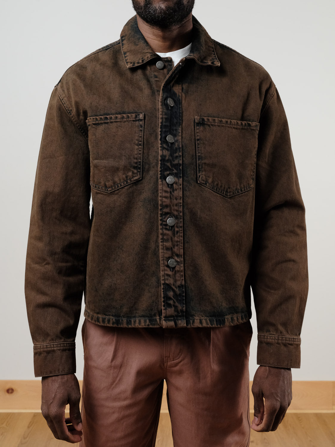 A person wears the !SOLID Rip Vintage Washed Denim Jacket and brown pants, standing indoors against a plain light-colored wall and wooden floor.