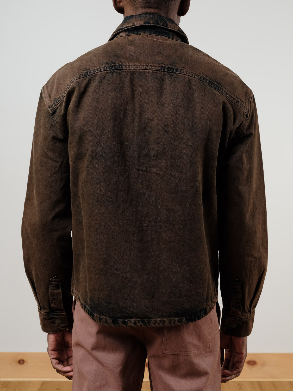 A person faces away from the camera, wearing the !SOLID Rip Vintage Washed Denim Jacket in faded brown and light brown pants, set against a light background.