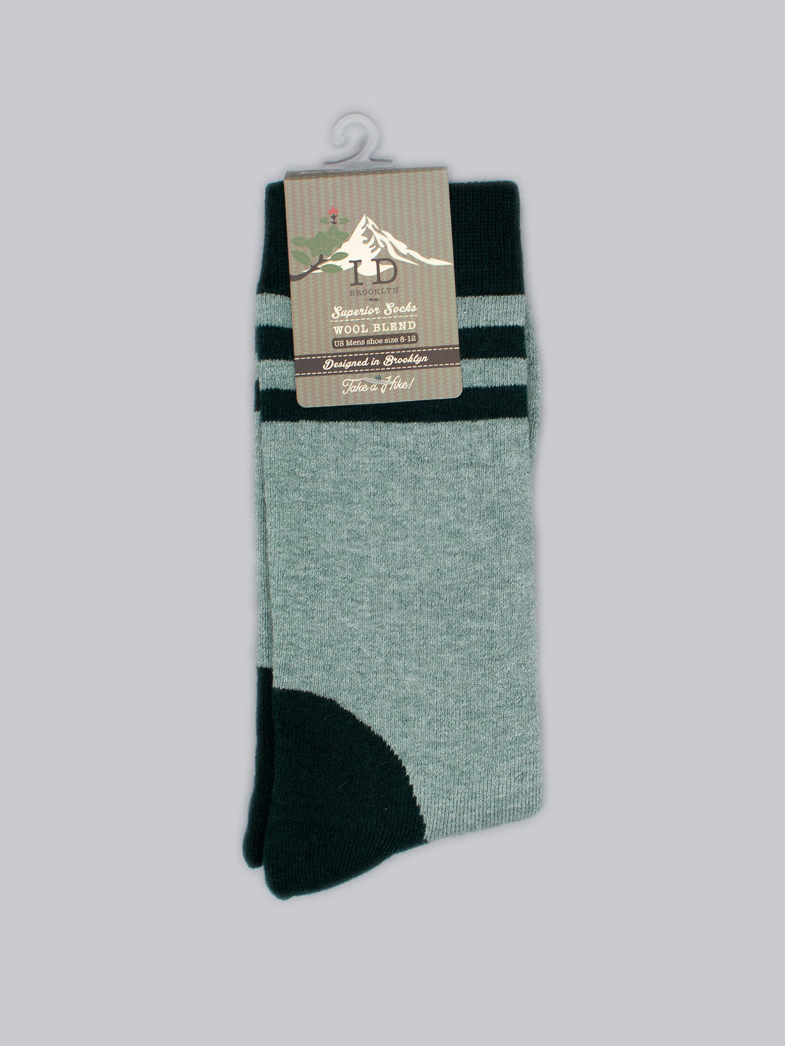 The Rockies Merino Wool Socks by ID Menswear are green and black with a decorative label showcasing text and a horse silhouette. These durable socks feature a solid green base, black toes and heel, plus two black stripes near the top, offering both style and warmth.