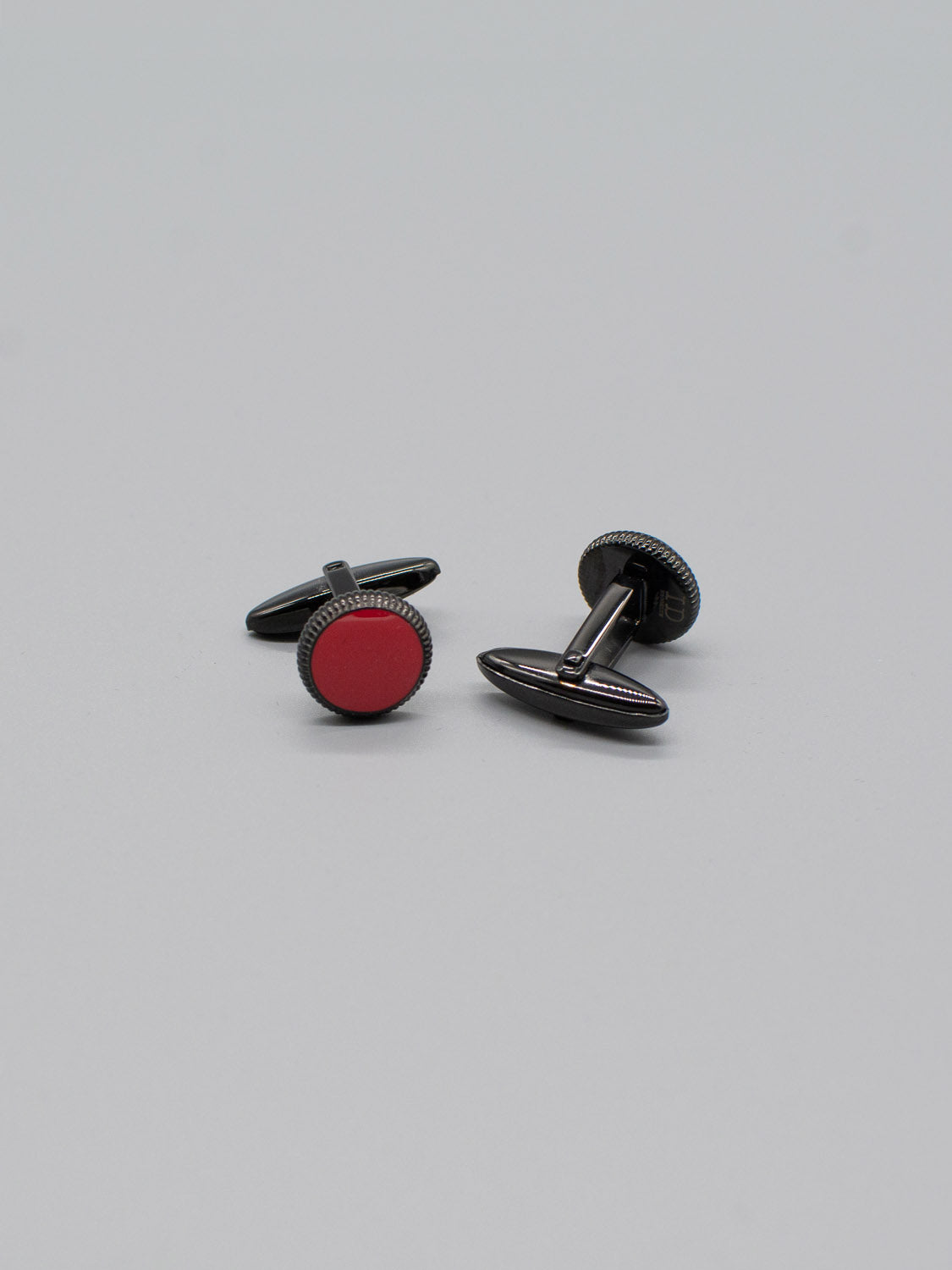 Two Black Gold Plated Steel Enamel Cufflinks by ID Menswear are shown on a gray background, showcasing their round red enamel inlays with black edges and backs, positioned at various angles.
