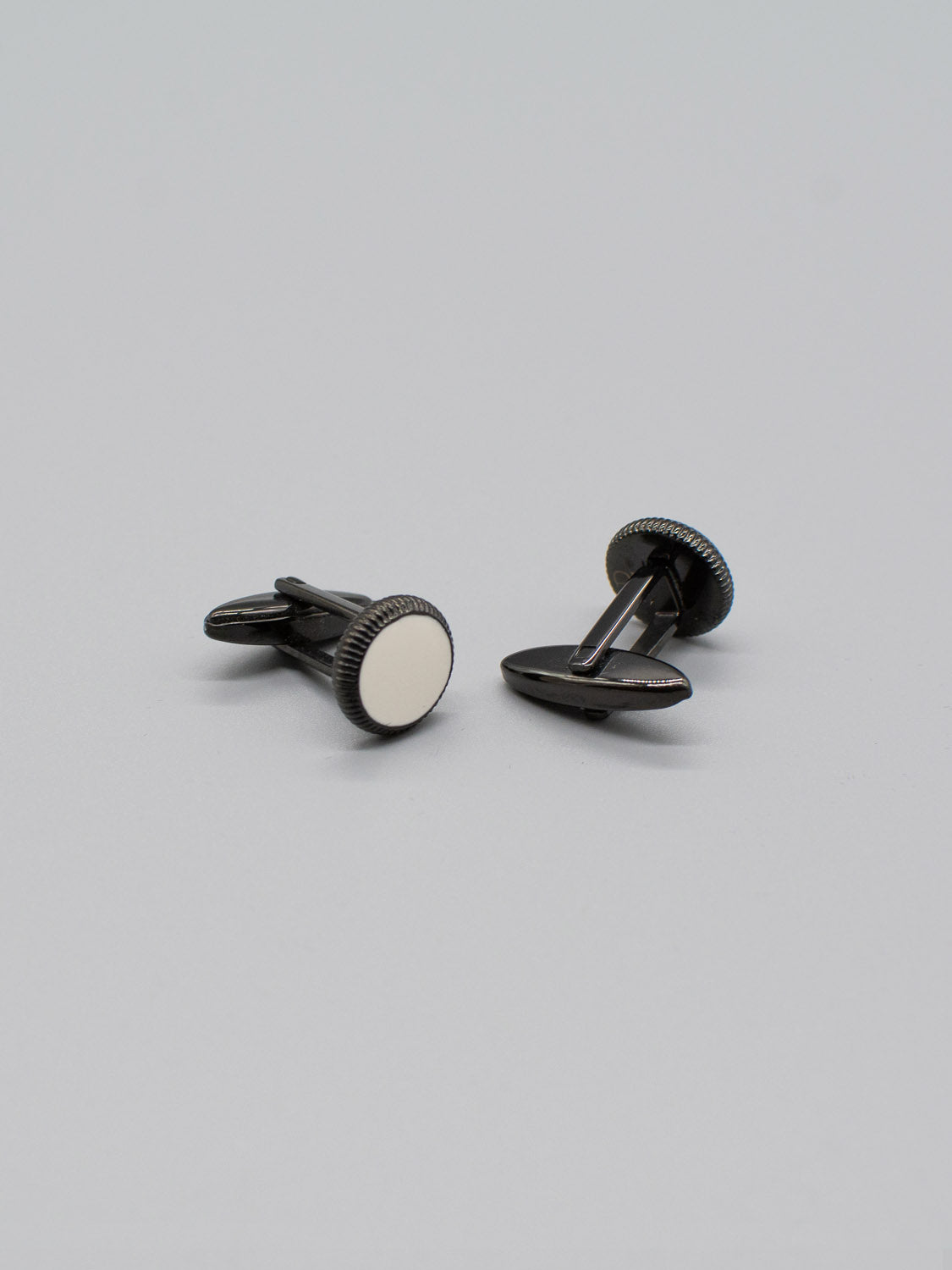 ID Menswears Black Gold Plated Steel Enamel Cufflinks, featuring round white enamel inlays, are displayed on a light gray background.