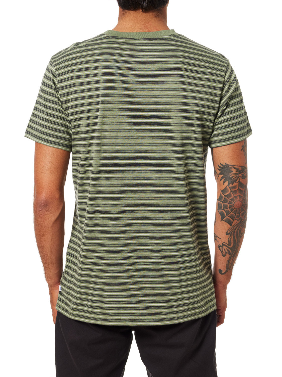 A tattooed individual on their left arm wears a Katin Rural Pocket Tee, a green and black stripe knit T-shirt made from premium cotton. Seen from behind, it pairs perfectly with black pants for a relaxed look.