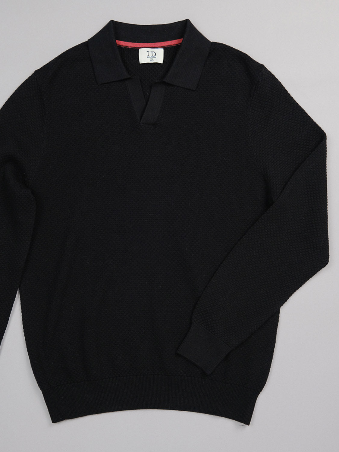 The black long-sleeve sweater, resembling the Seattle Long Sleeve Cotton Polo by ID Menswear, features a textured pattern with a collar and small V-neck. Perfect for smart-casual occasions, it is displayed flat on a gray background.