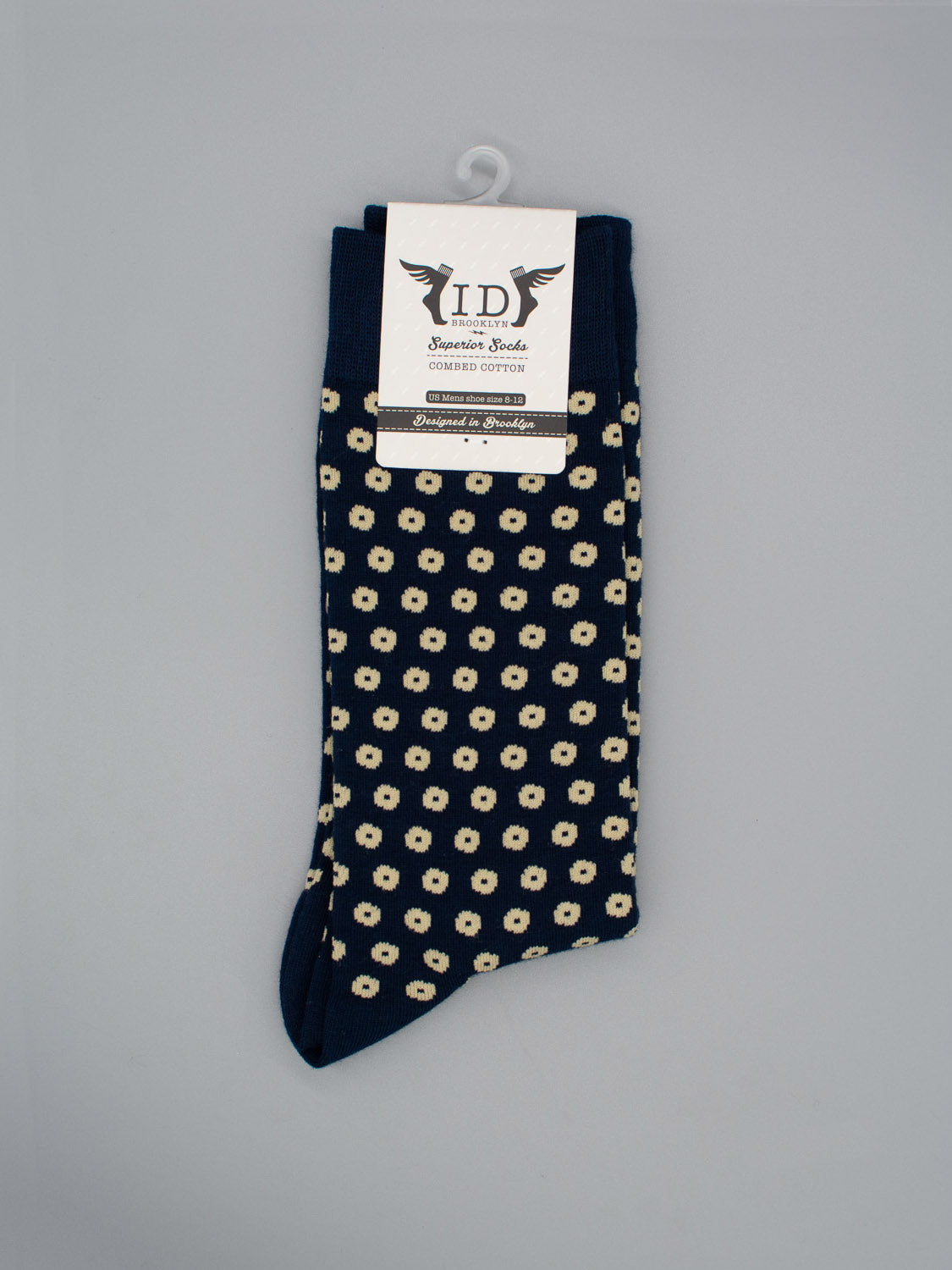 A pair of Shibori Graphic Socks by ID Menswear, crafted from soft combed cotton in dark blue with small white and yellow flowers, neatly folded with a branded label and set against a plain gray background.