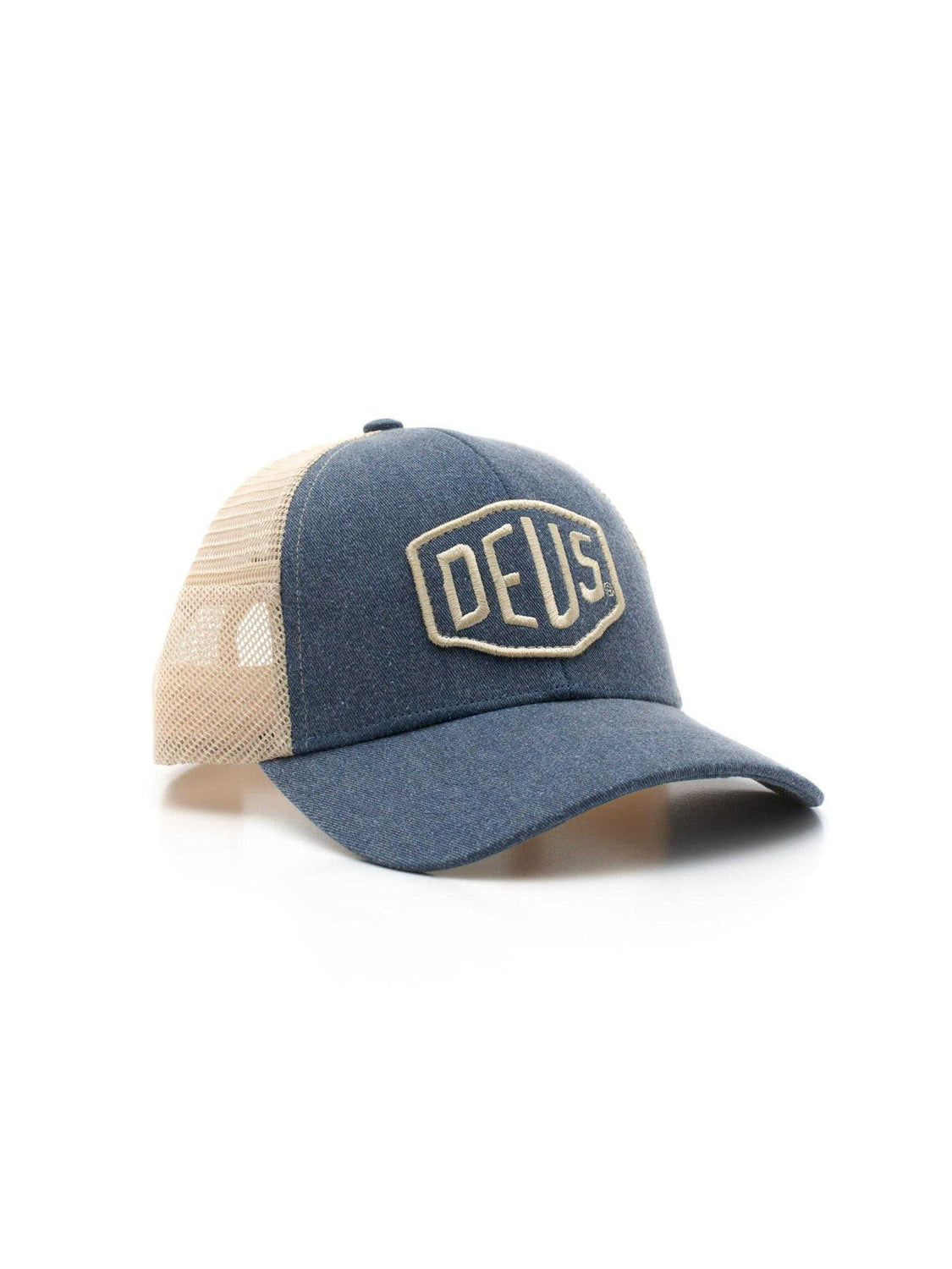 The Deus Shield Trucker is a blue and beige cotton canvas hat featuring a mesh back, curved brim, large embroidered "DEUS" on the front, and an adjustable classic snapback closure.