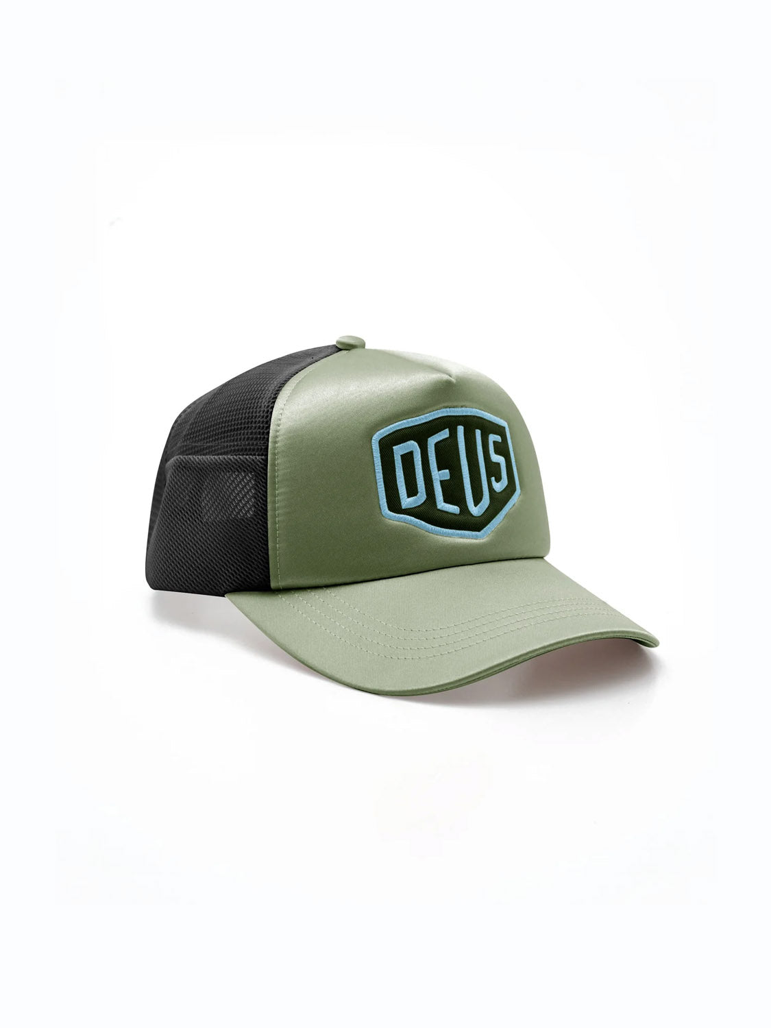 The Deus Shield Luxx Trucker is a green and black hat with a mesh back and curved brim. A bold "DEUS" outlined in blue appears on the front patch. The cap is shown on a plain white background.