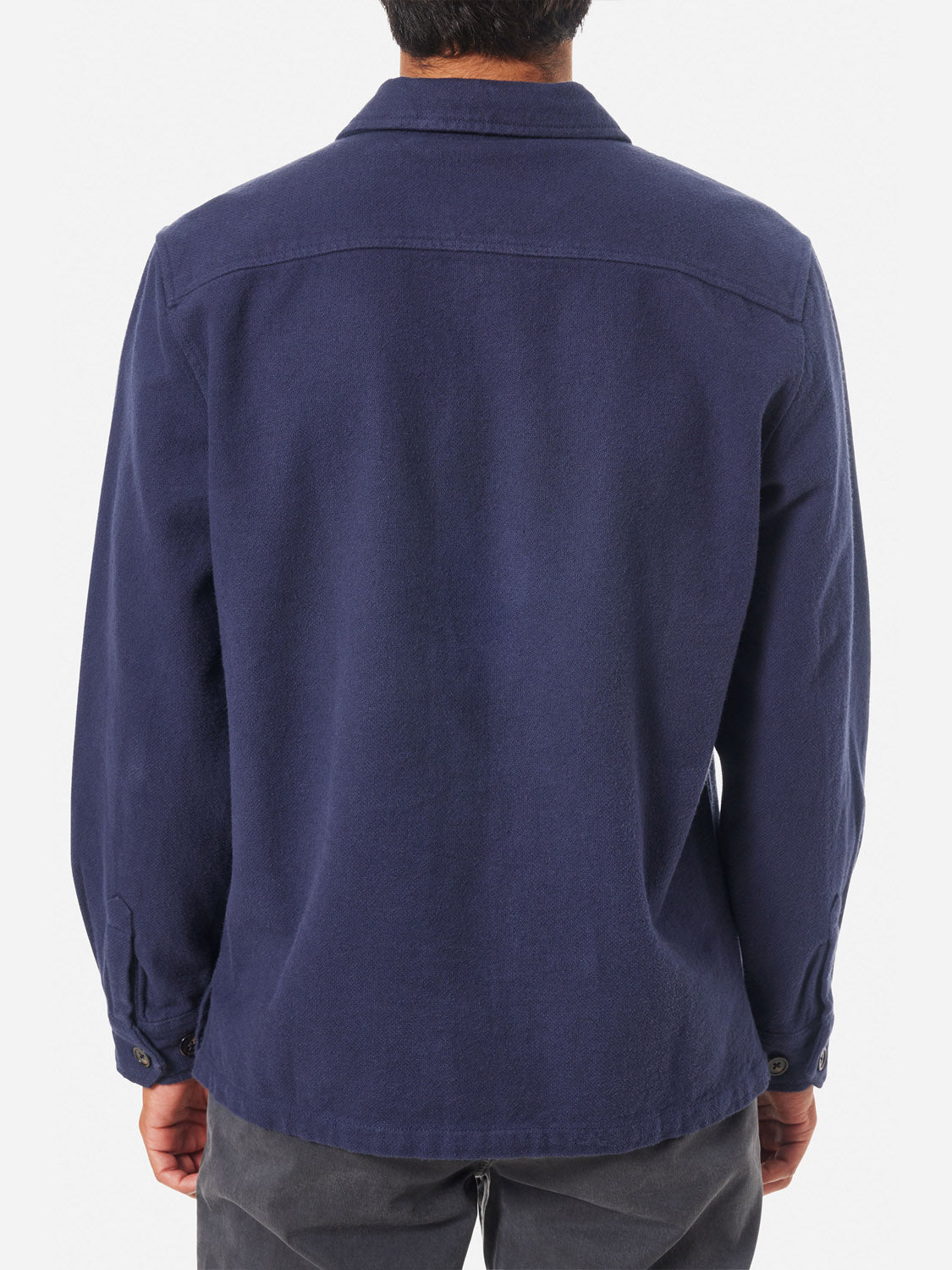 A person is shown from the back wearing the Katin Shiloh Solid Flannel Shirt in navy, featuring a collar and cuffs, paired with dark gray pants. The heavyweight cotton shirt stands out against the plain white background.