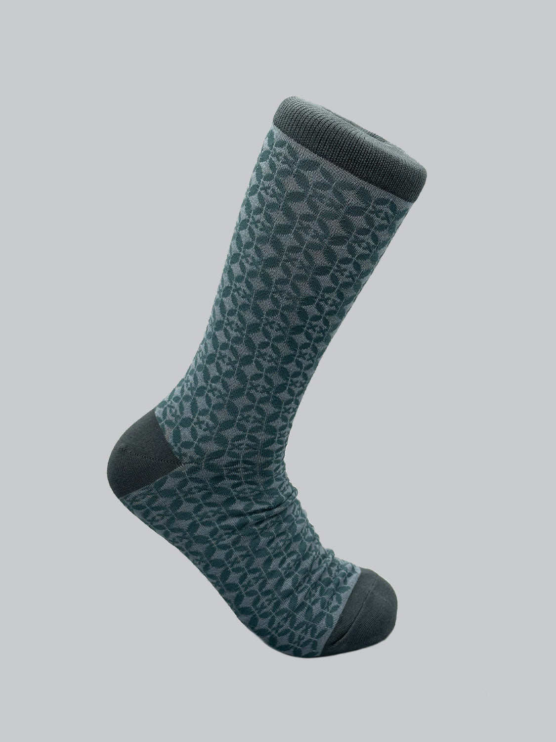 The Shippo Graphic Socks by ID Menswear are single gray socks with a textured leaf pattern and darker gray toe, heel, and cuff. Crafted from premium combed cotton, they offer comfort with an elegant geometric design against a plain backdrop.